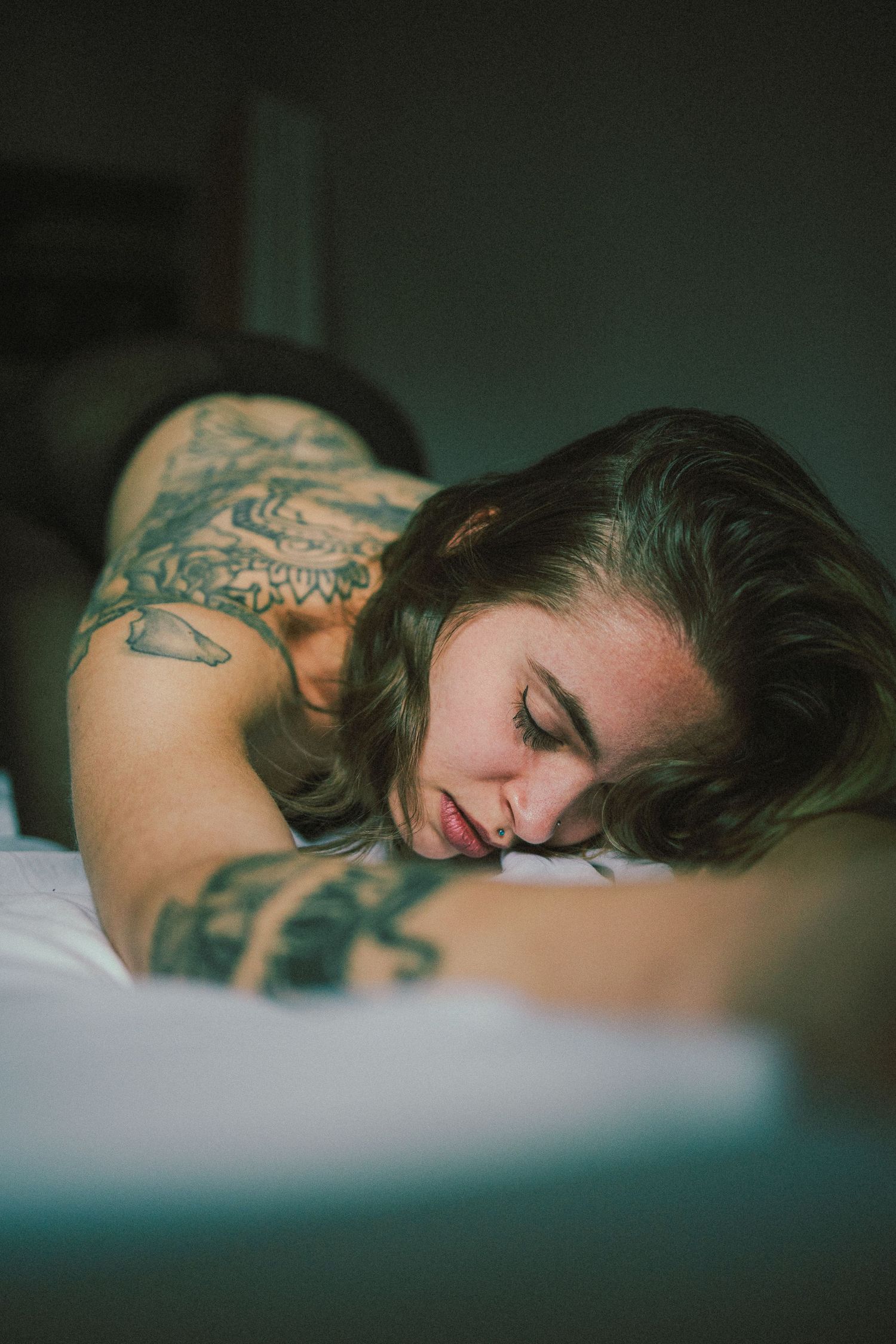 Intimate portrait showing tattooed shoulder in soft natural lighting.