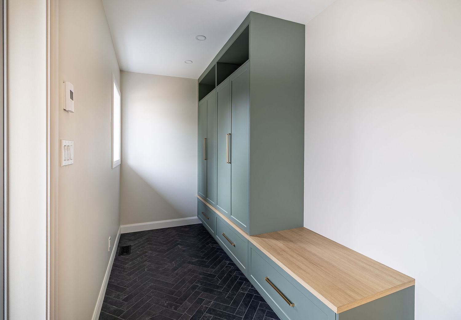 Modern hallway with built-in storage bench and sage green accent wall.
