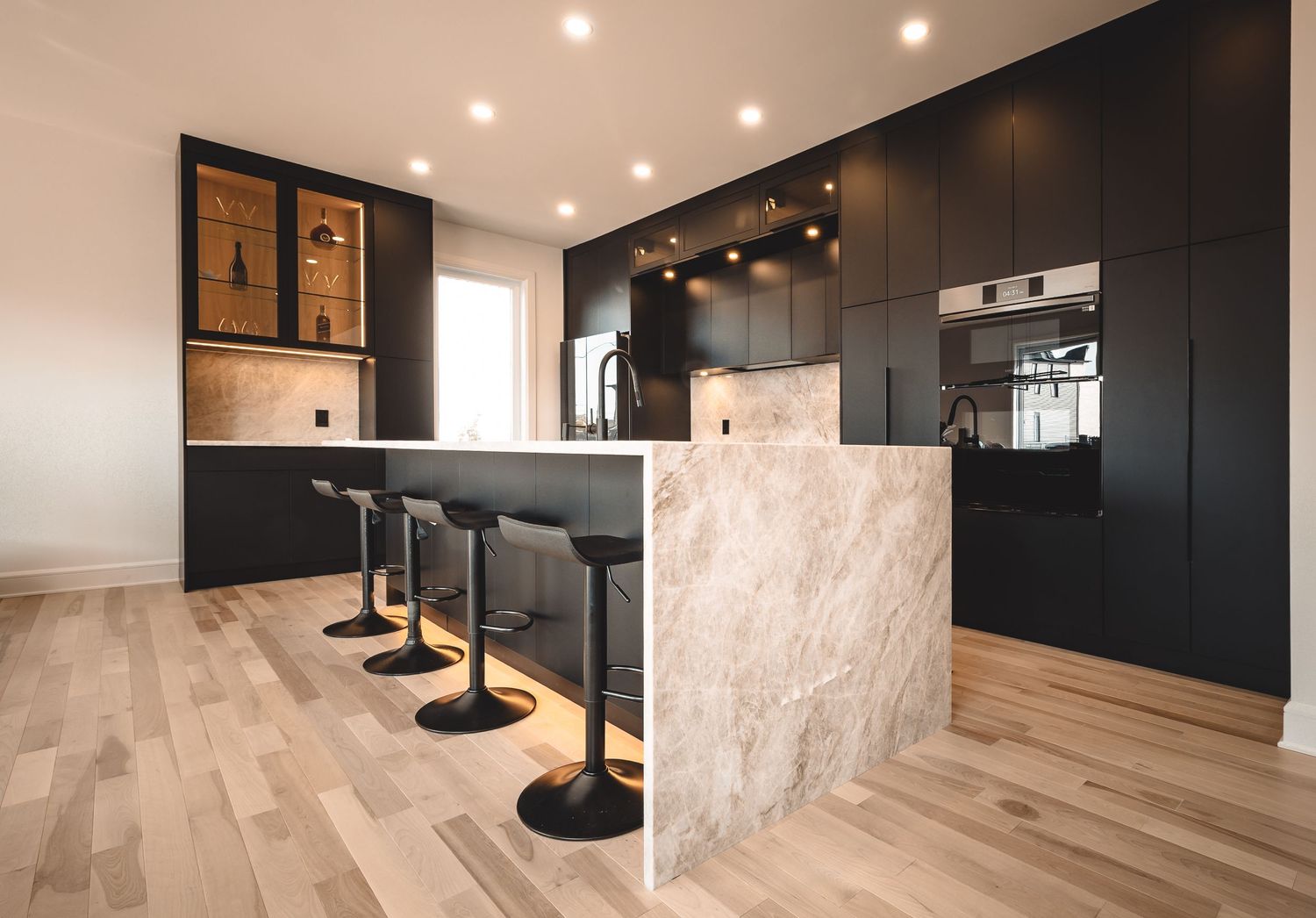 Modern living space with black accent wall, light hardwood floors, and bar-height seating area.