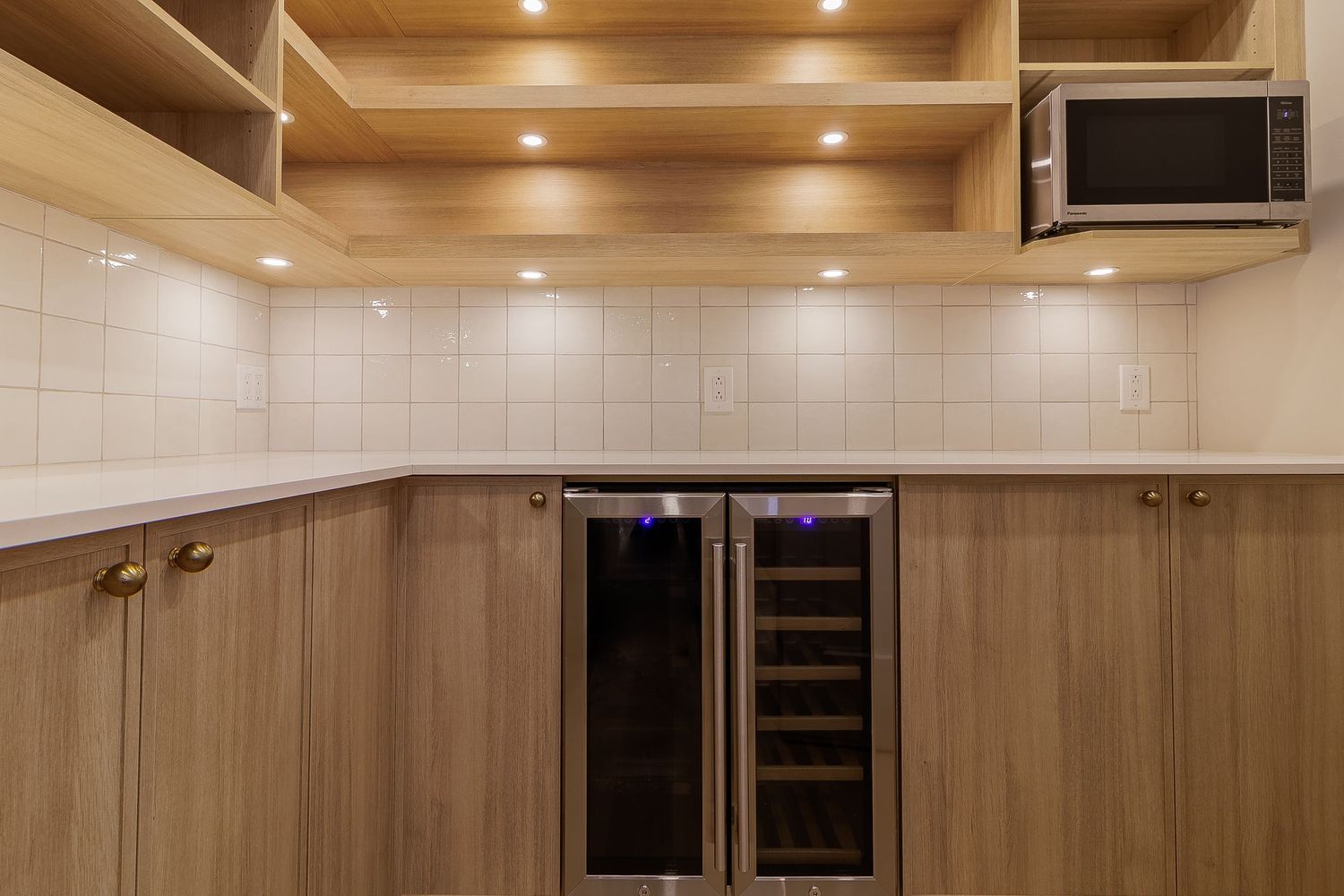 Wooden ceiling with recessed lighting and white tile backsplash in modern kitchen.