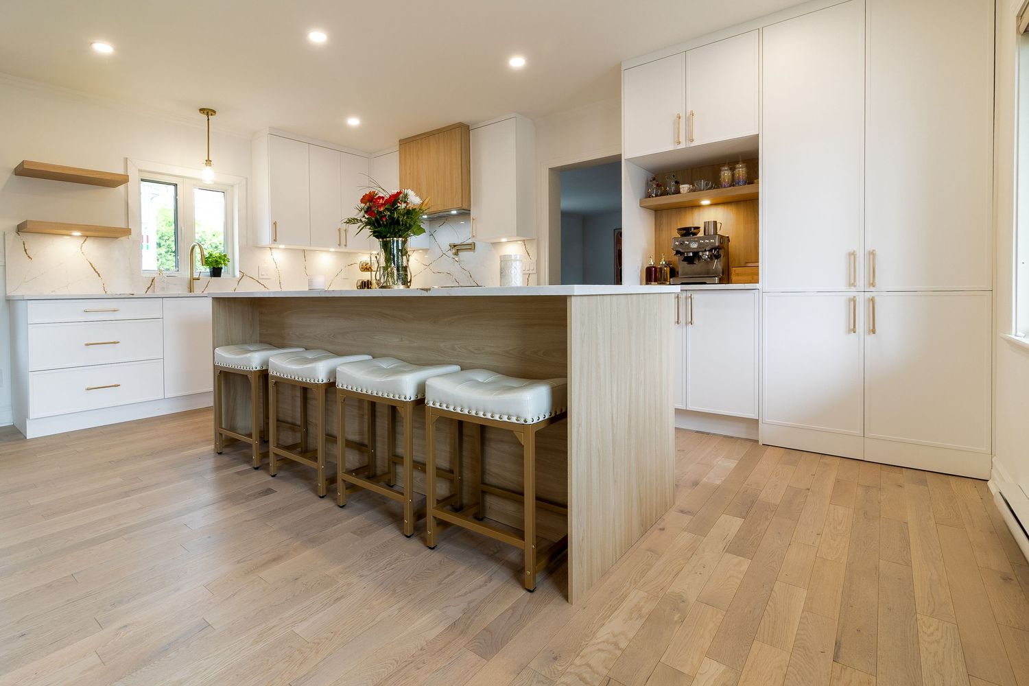 Open concept living space with light hardwood floors and white kitchen cabinetry.