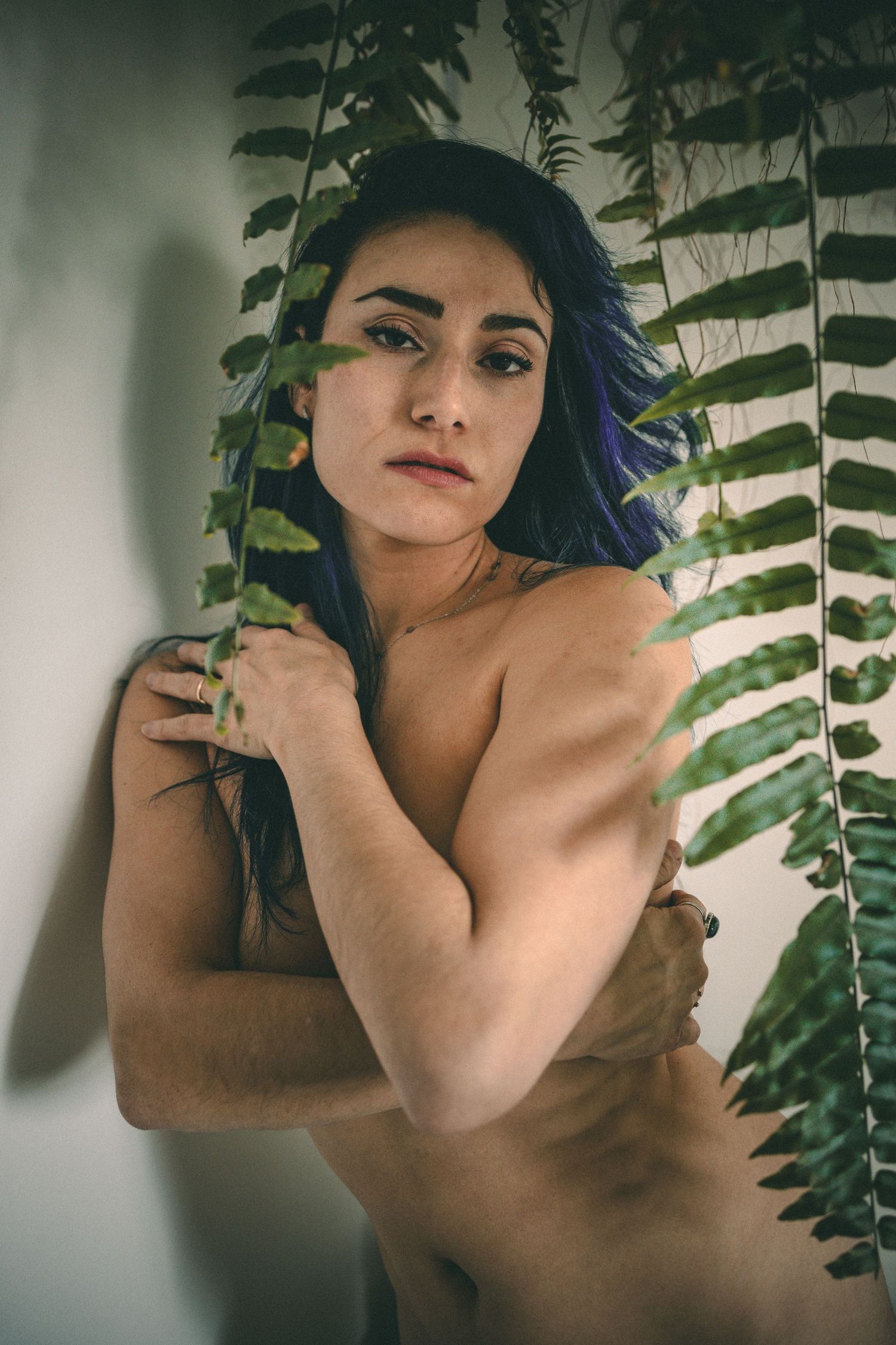 Intimate portrait with tropical plant leaves creating natural shadows and texture.