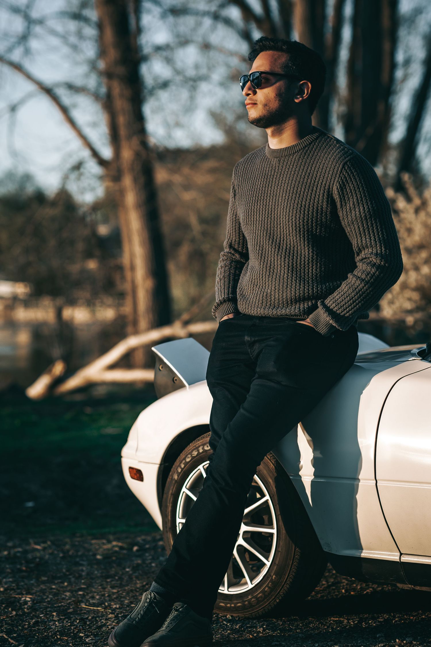 Fashion portrait of person in ribbed sweater posed against white vintage car.