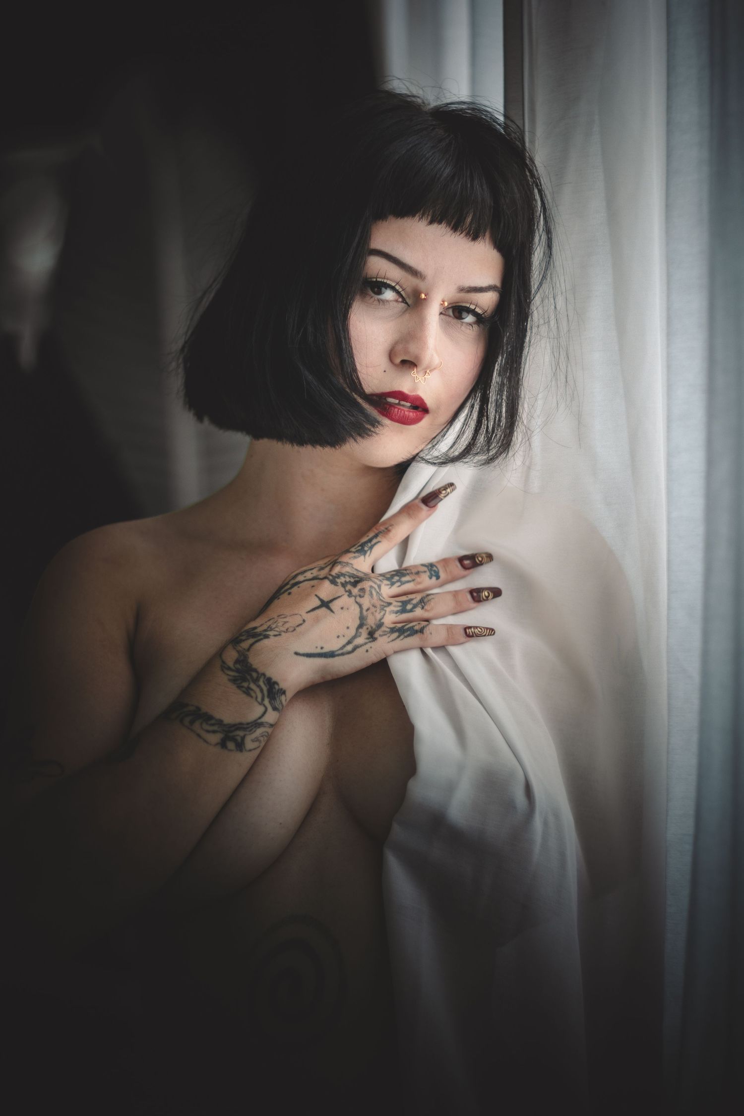 Artistic black and white portrait series showing a dark-haired figure with tattoos against soft window light.