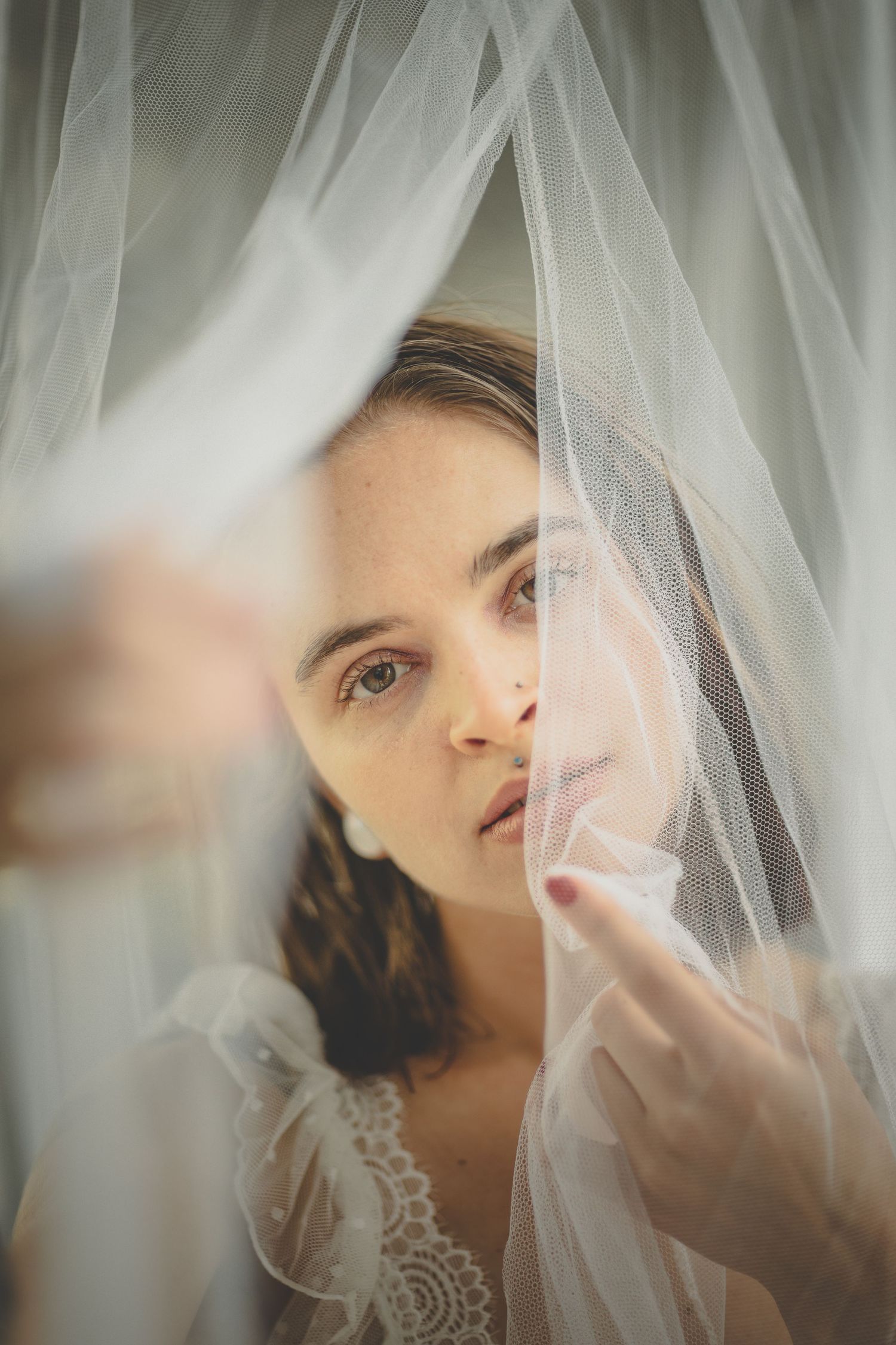 Ethereal bridal portrait through delicate white tulle veil creating a dreamy effect.