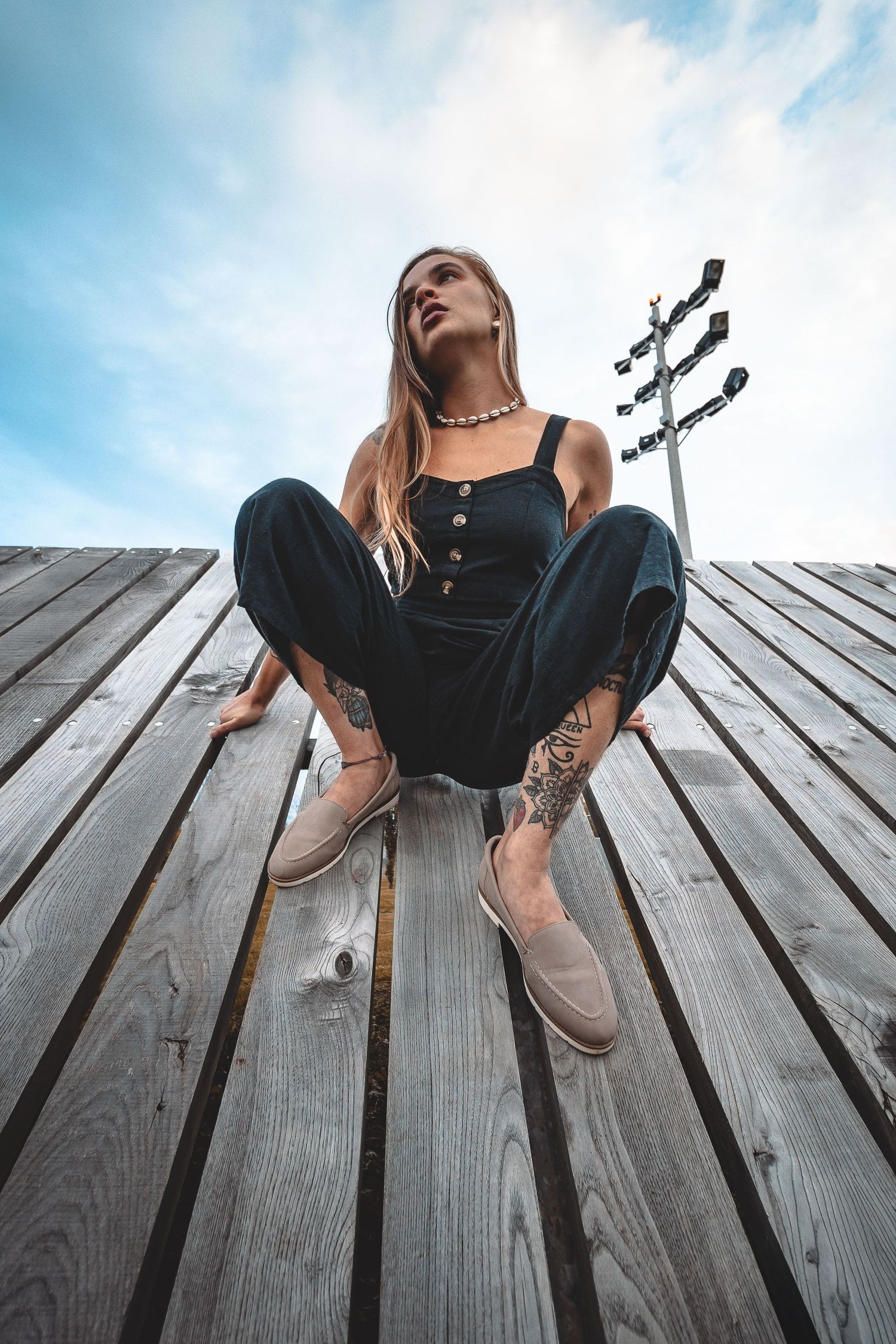 Creative low angle shots on wooden deck planks showing boots and tattoos in natural lighting.