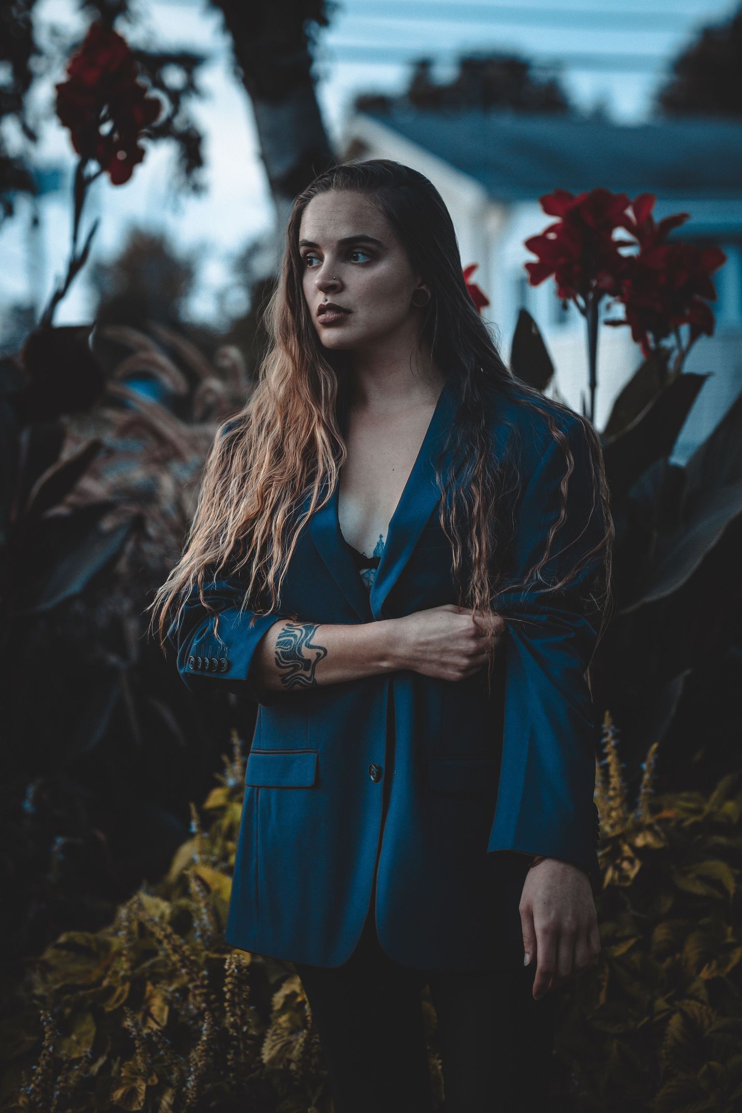 Moody portrait in a blue coat against autumn foliage with dramatic lighting and atmospheric mood.