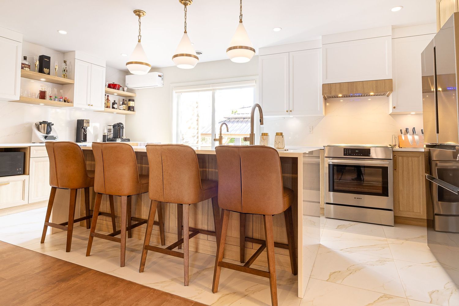 Bright open concept living area with pendant lights and brown leather bar stools at the kitchen counter.
