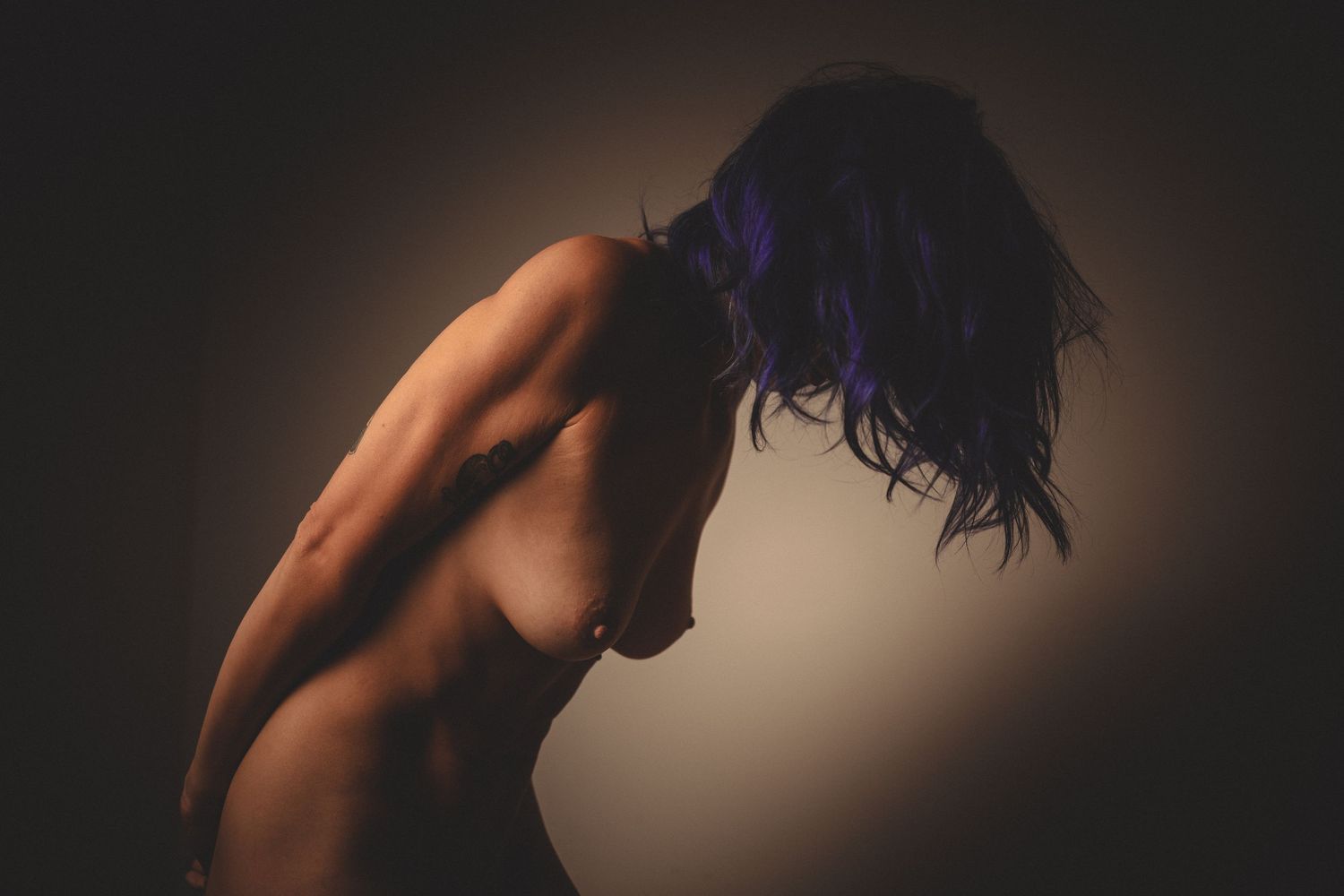Silhouetted figure against dark background in intimate artistic portrait.