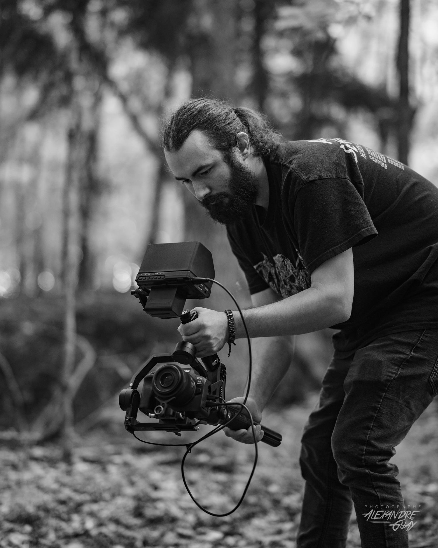 Black and white series of a photographer using camera equipment in a forest setting.