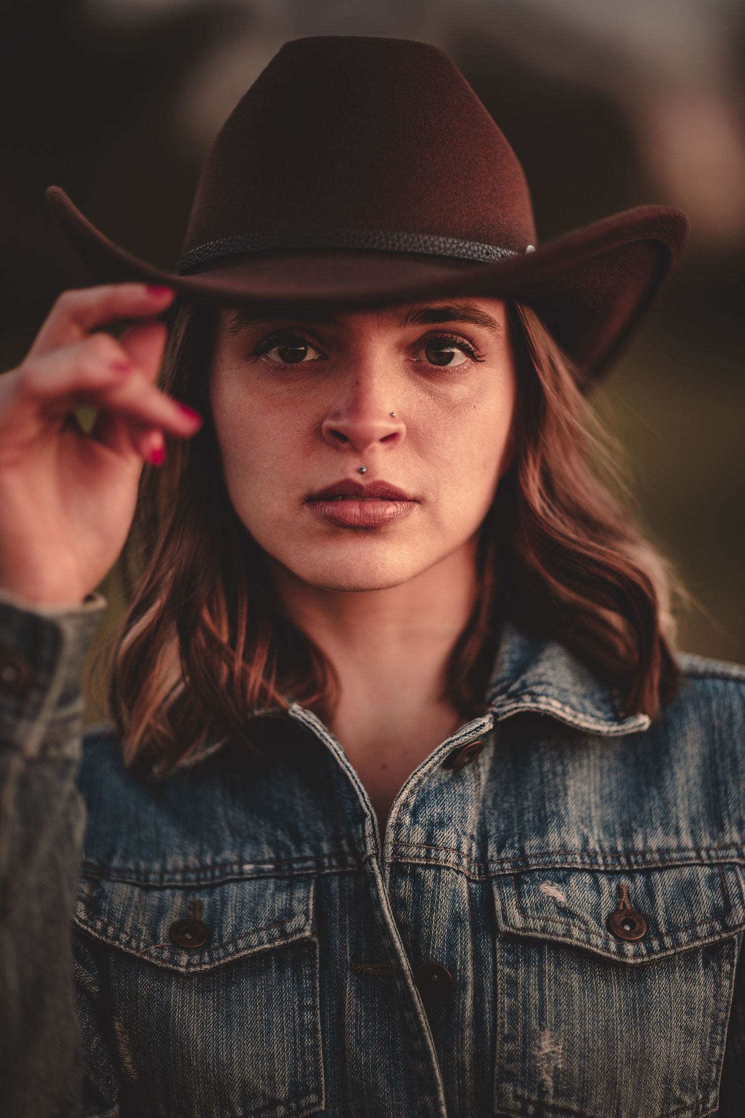 A stylish brown fedora hat worn with a denim jacket in a warm-toned portrait photograph.