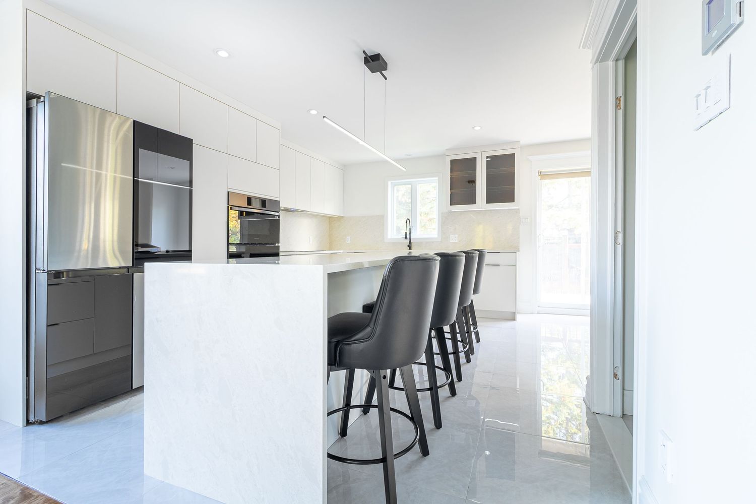Bright white open concept living space with modern kitchen and dining area visible through doorway.