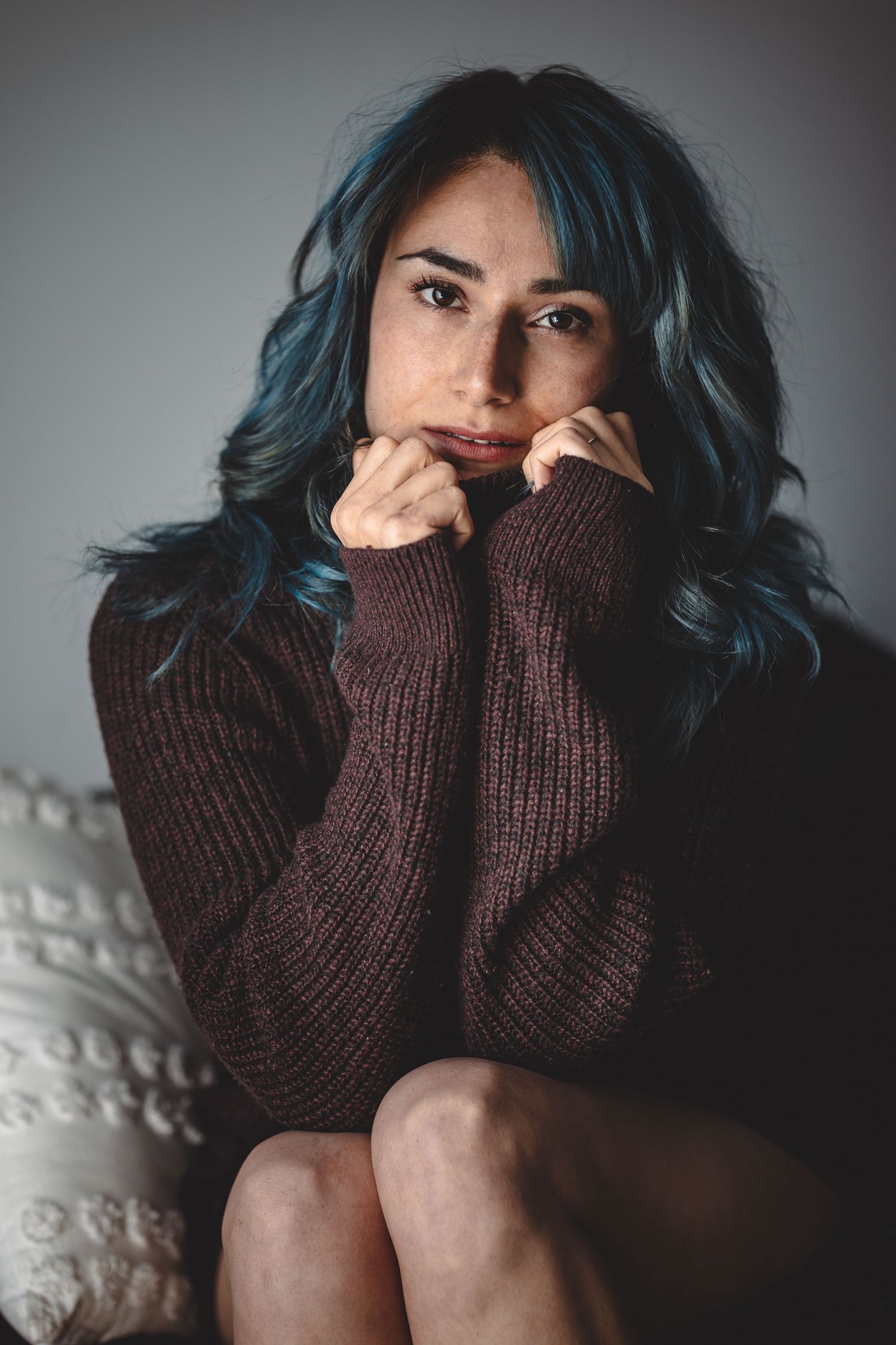 Cozy indoor portrait in brown sweater with moody lighting and intimate feel.