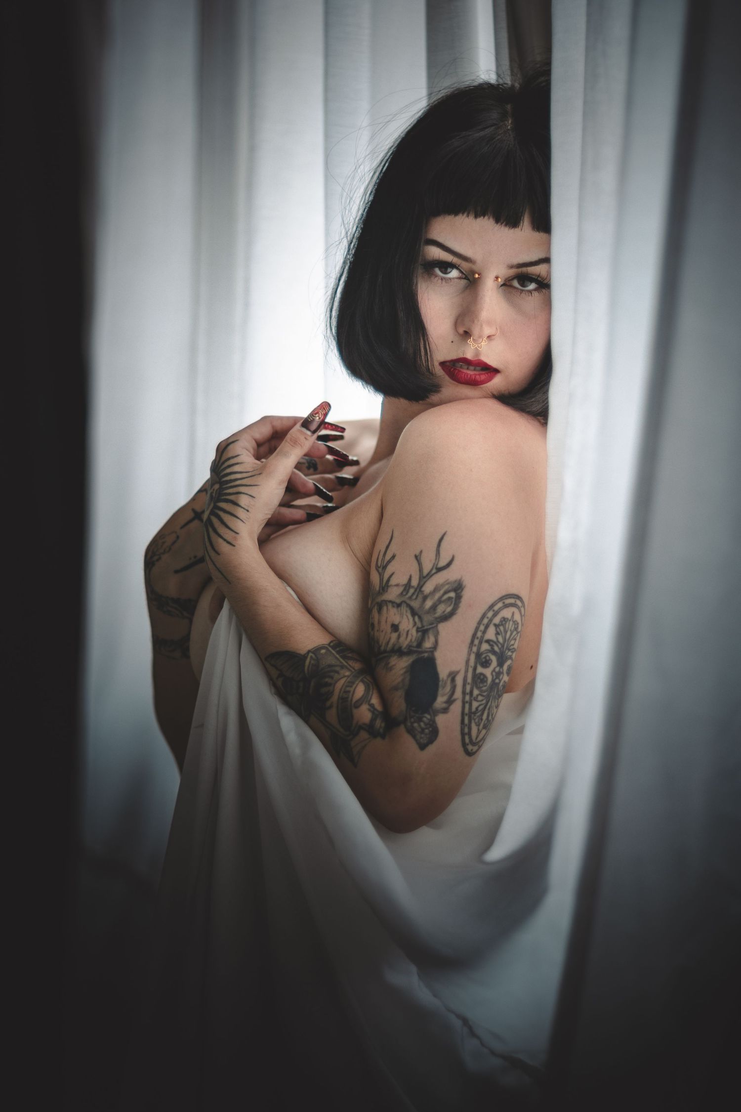 Sensual portrait series showcasing tattoo art and soft fabric textures against window light.