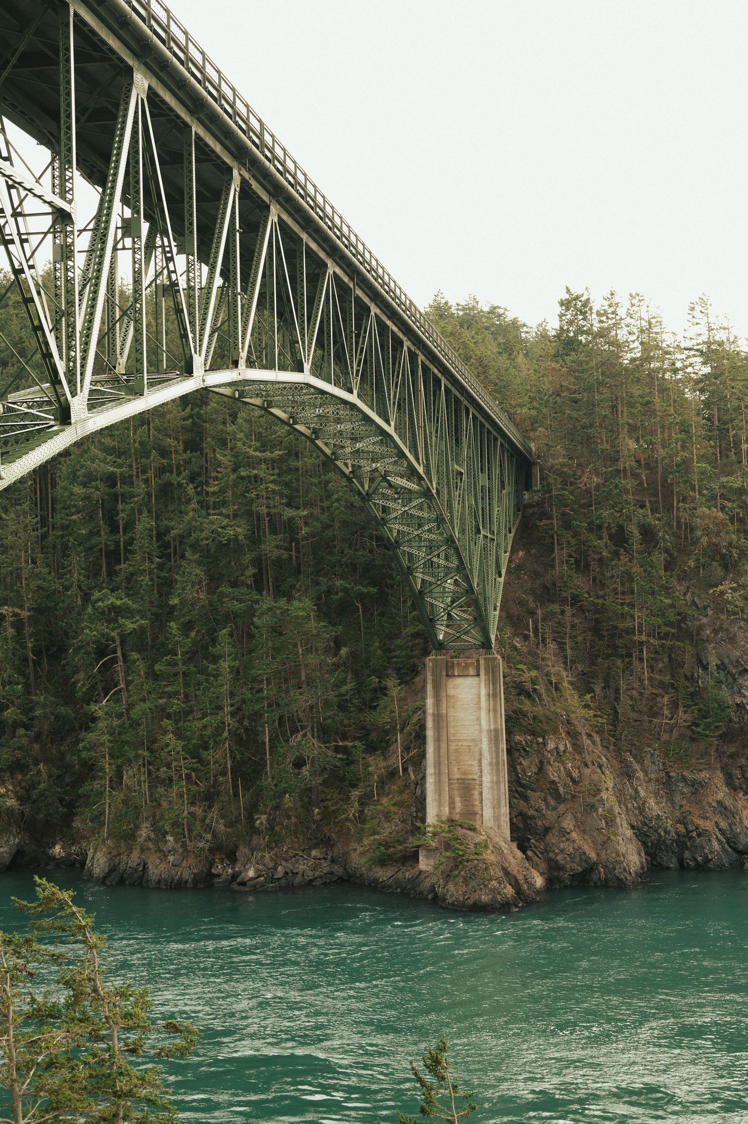 Steel arch bridge spans turquoise waters between evergreen cliffs at Deception Pass in Washington State.