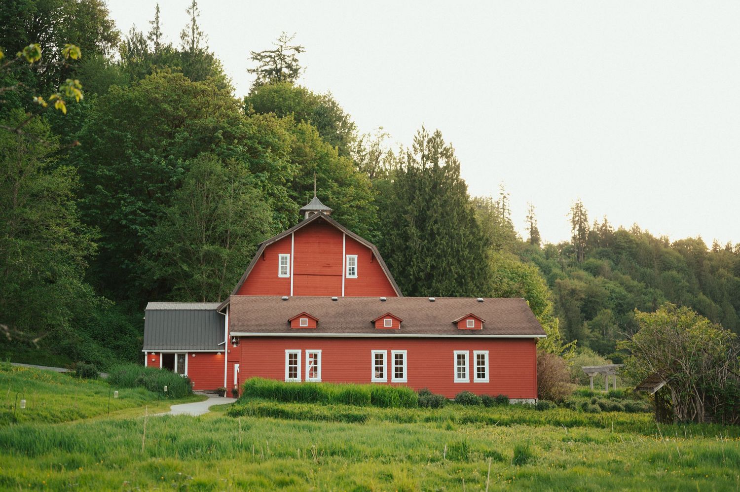 A panoramic view of a red barn building in a rural countryside setting.