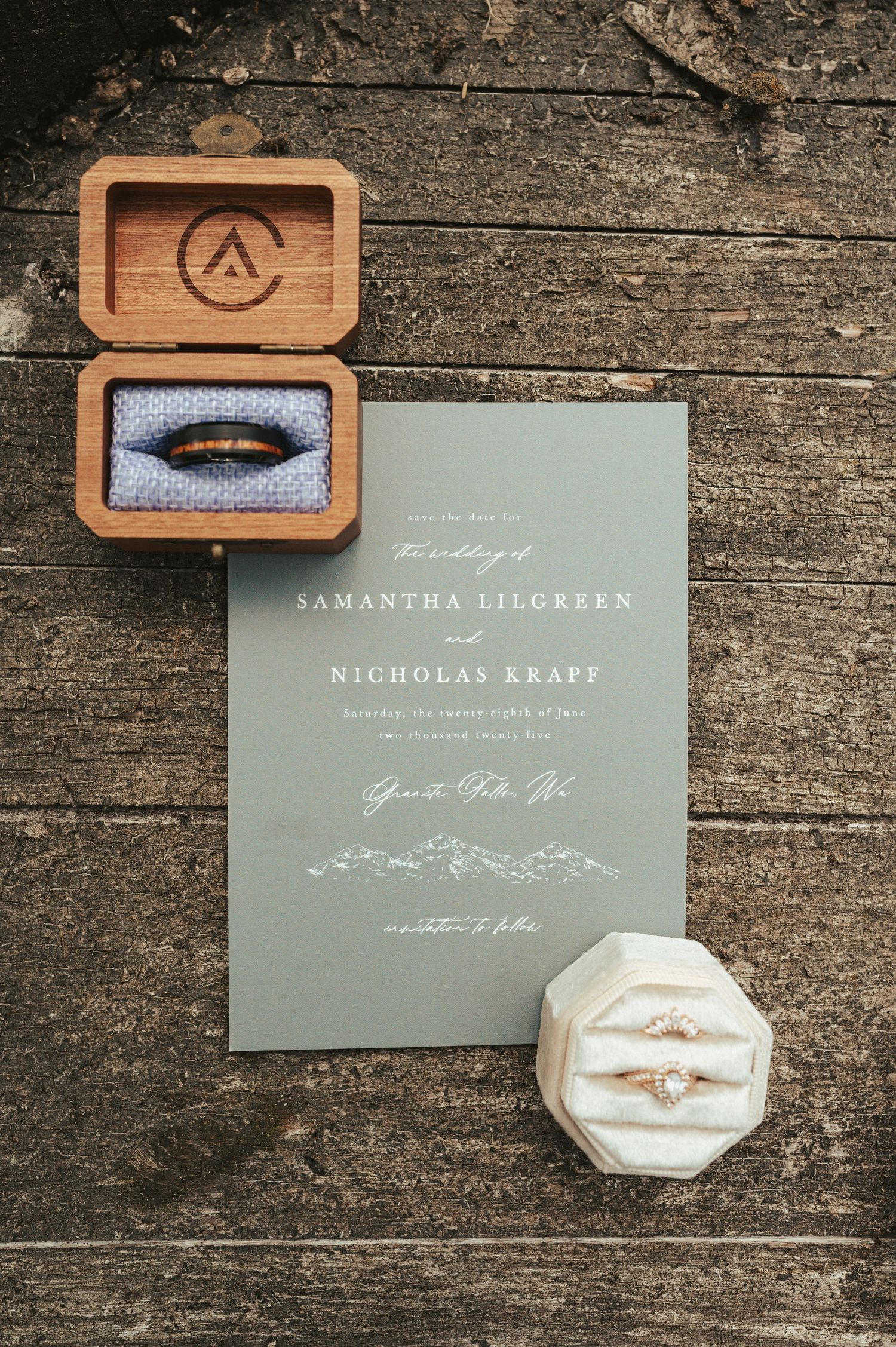 Wedding invitation and rings displayed on rustic wooden surface with custom wooden ring box.