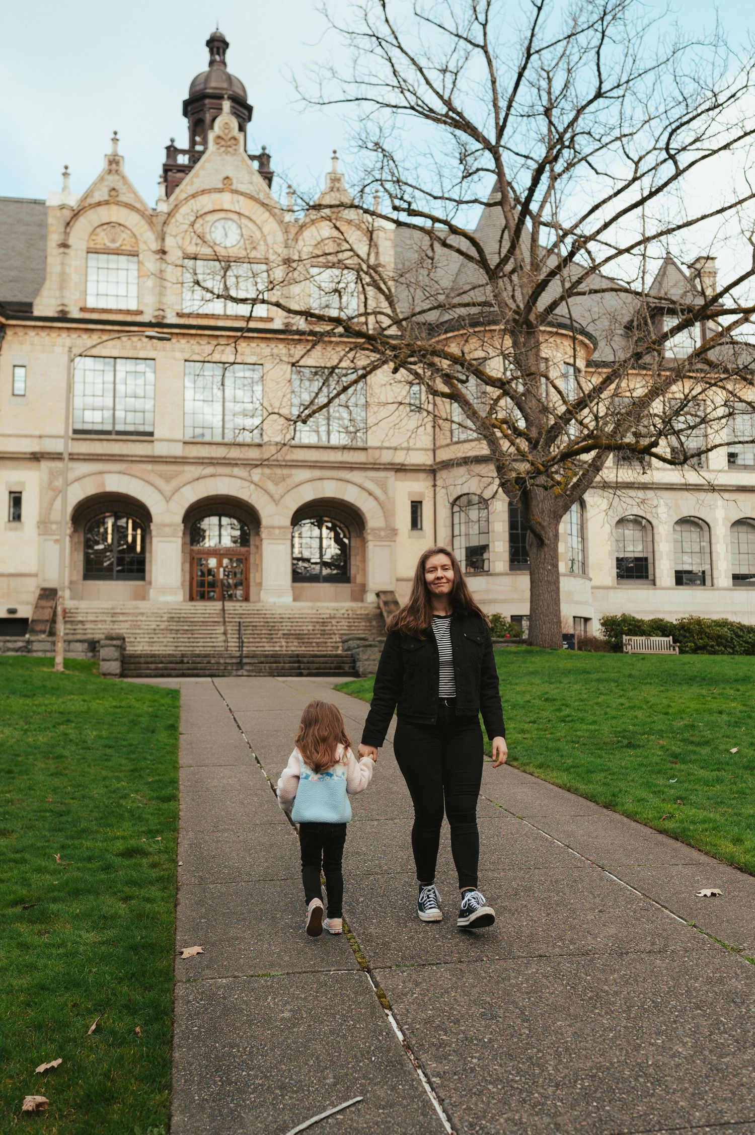 Historical building with ornate architecture serves as backdrop for family walking along pathway.