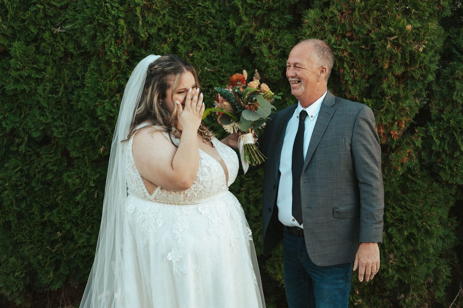 A touching emotional moment during an outdoor wedding with greenery backdrop.
