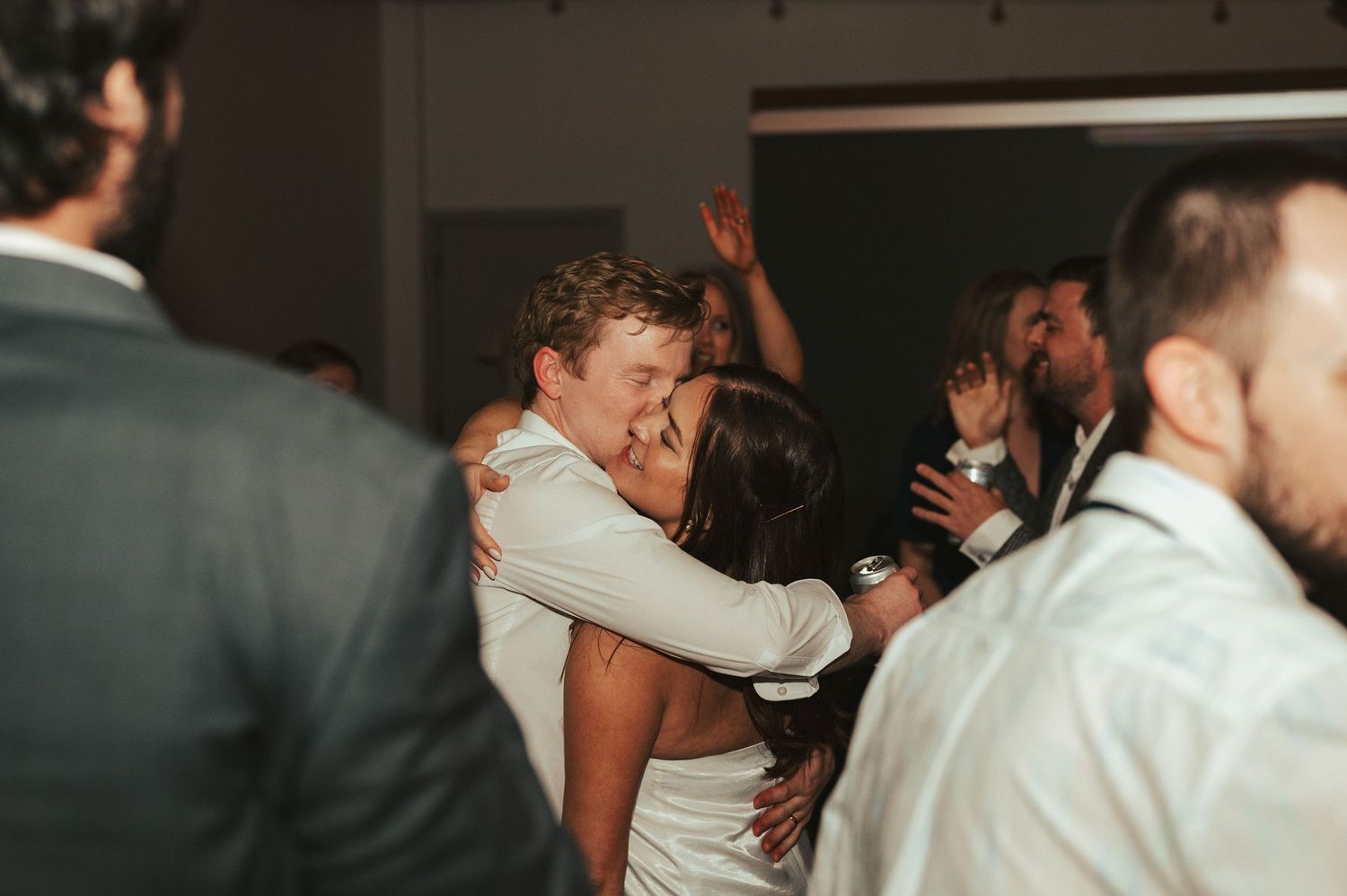 Wedding guests dance and celebrate on a dark dance floor at night.