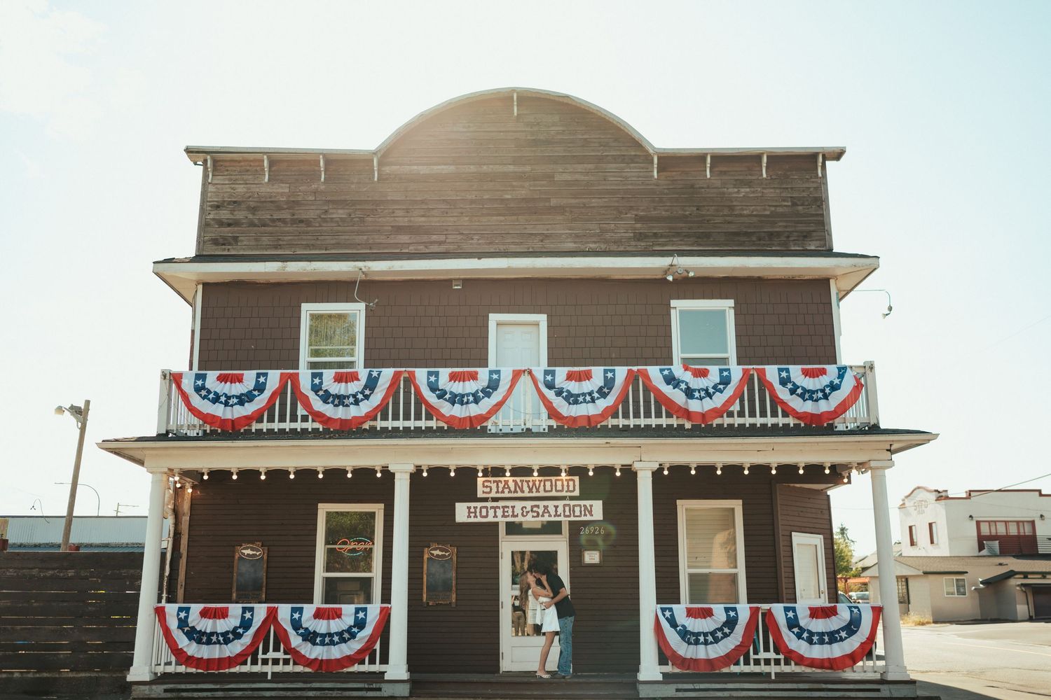 A rustic wooden building decorated with patriotic red white and blue bunting banners on its facade.