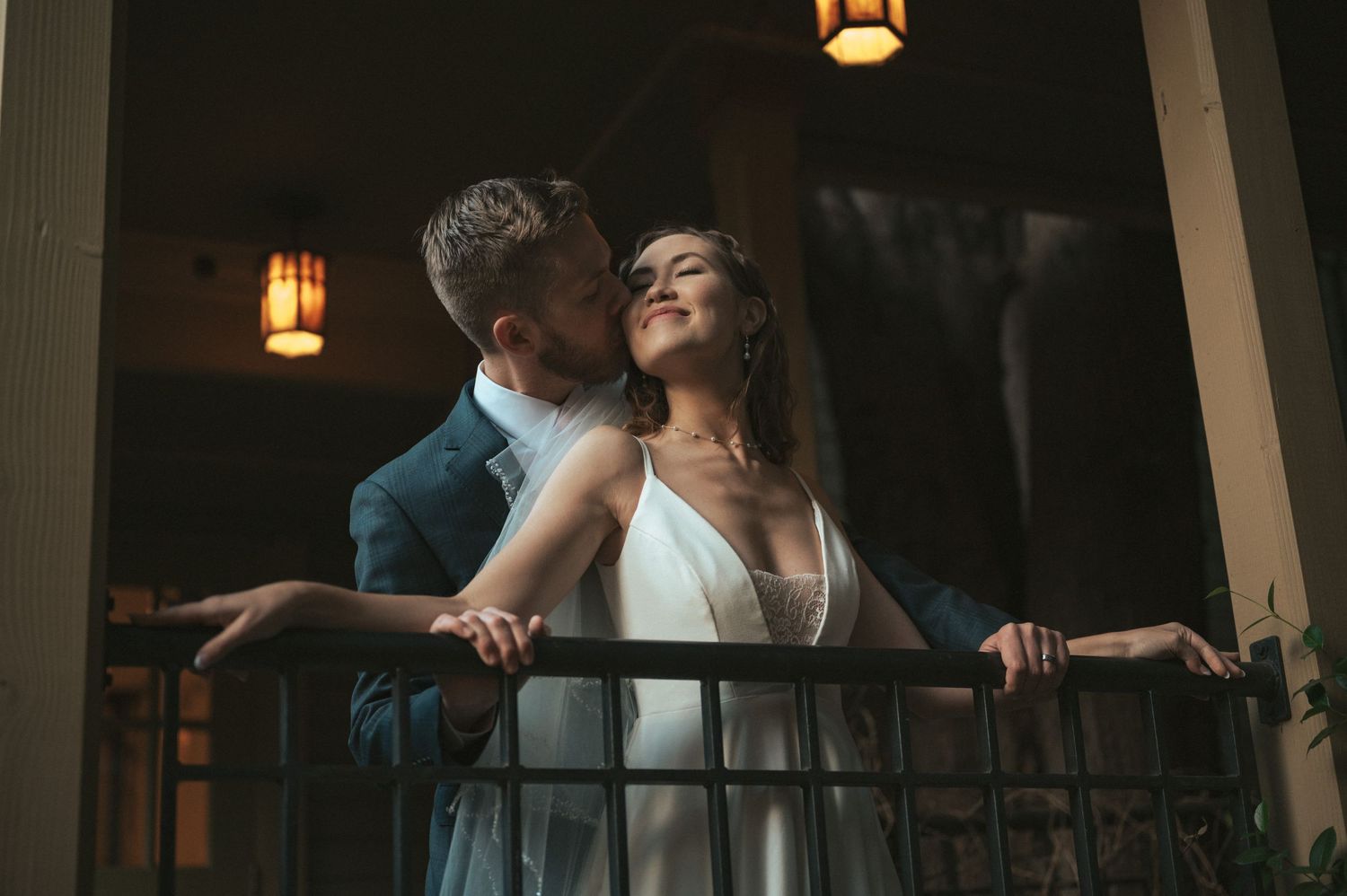 A romantic moment shared on a dimly lit balcony with lanterns creating ambient lighting.