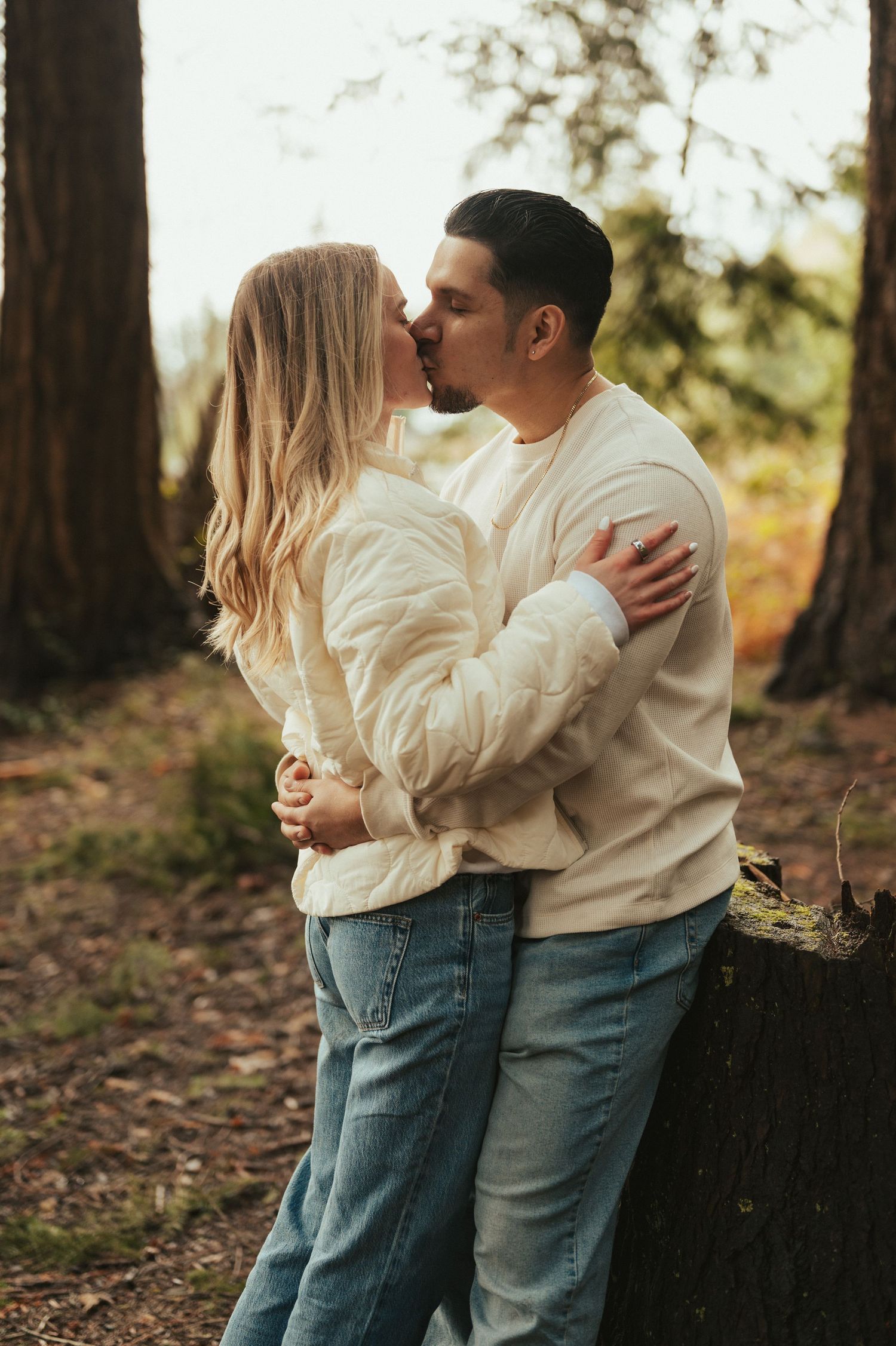 Two people in casual wear share intimate embraces against a forest backdrop.