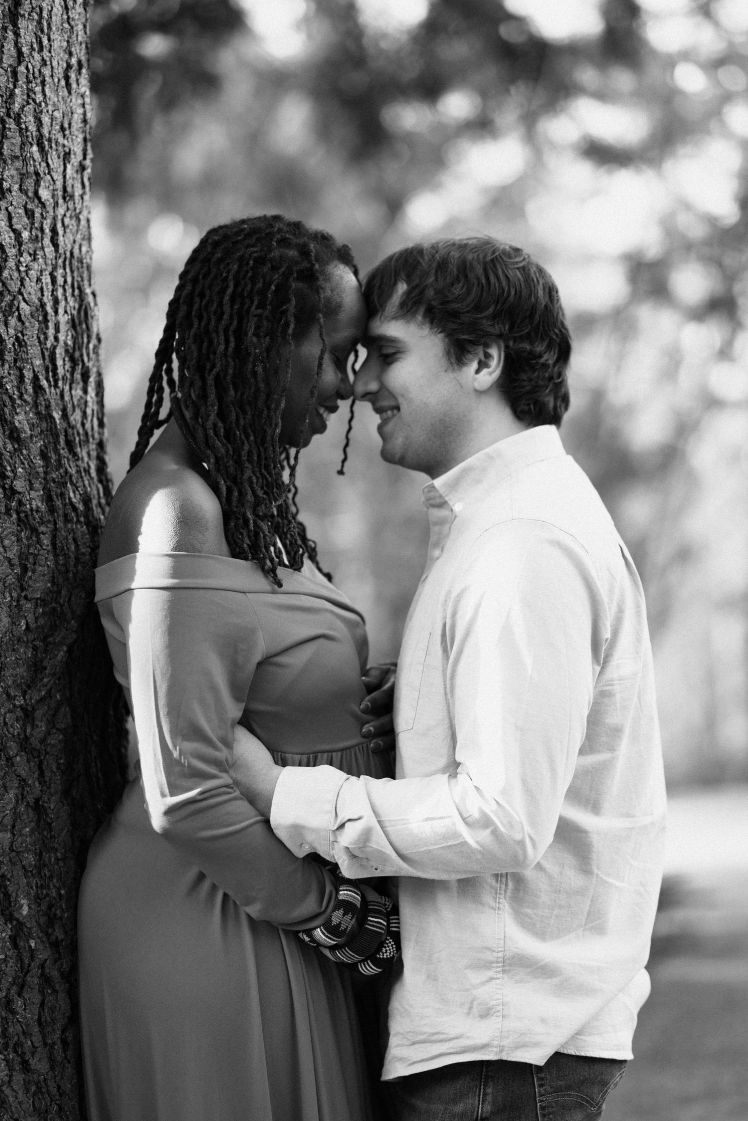 A black and white series of tender moments captured between two people near a tree.