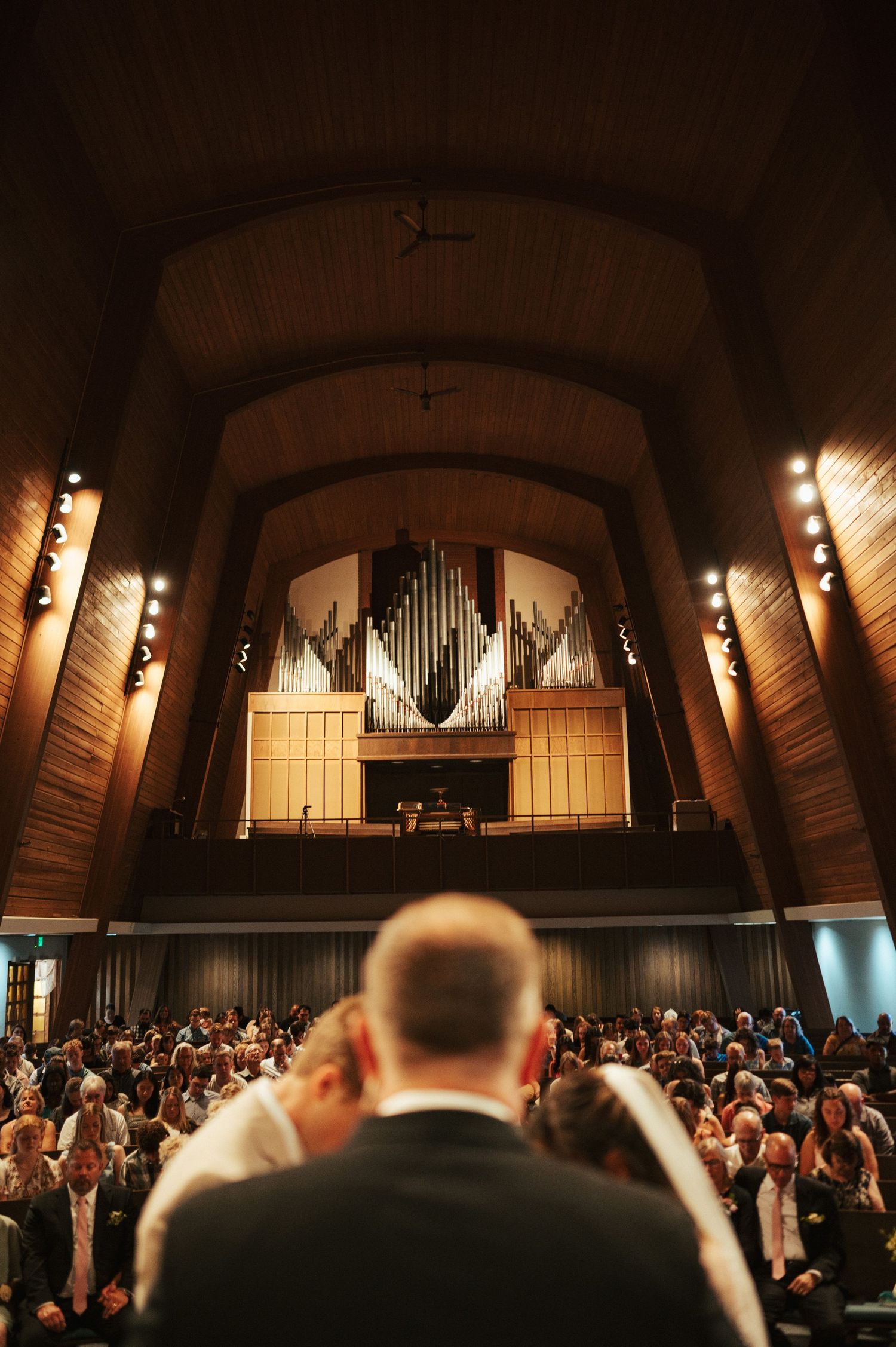 Church filled with guests and grand pipe organ during wedding ceremony.