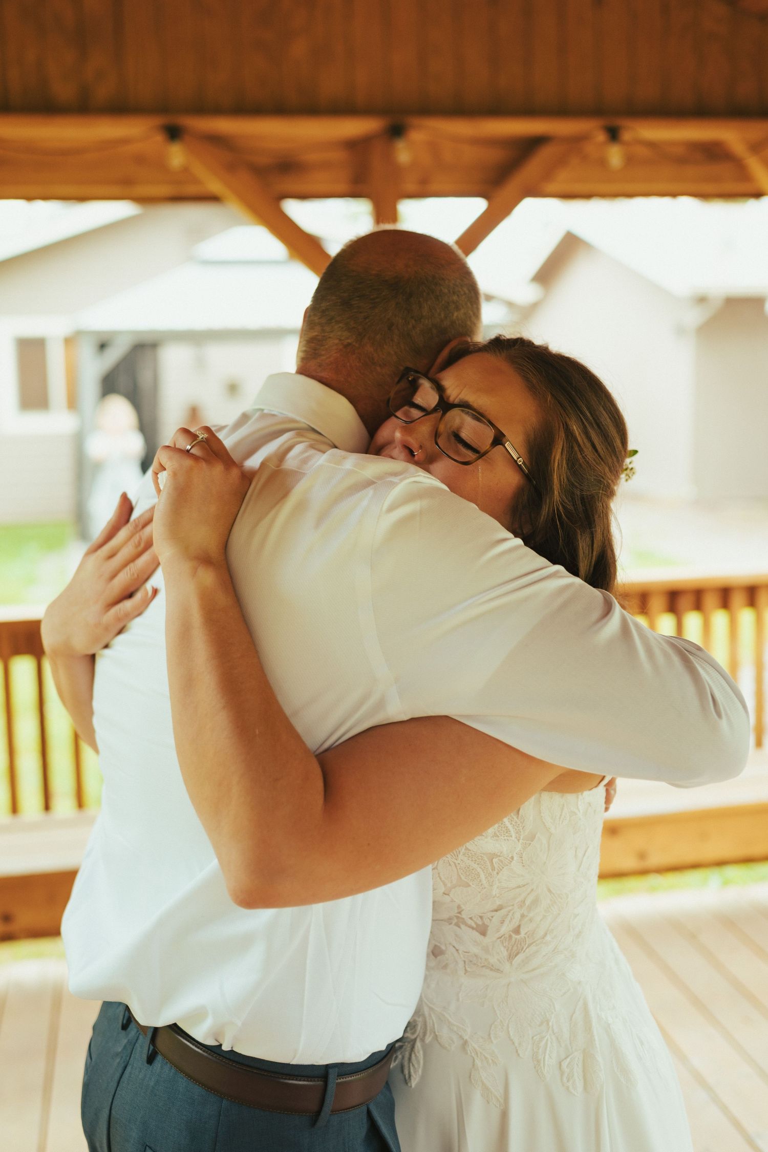 A warm embrace shared during an emotional wedding moment on a covered porch.