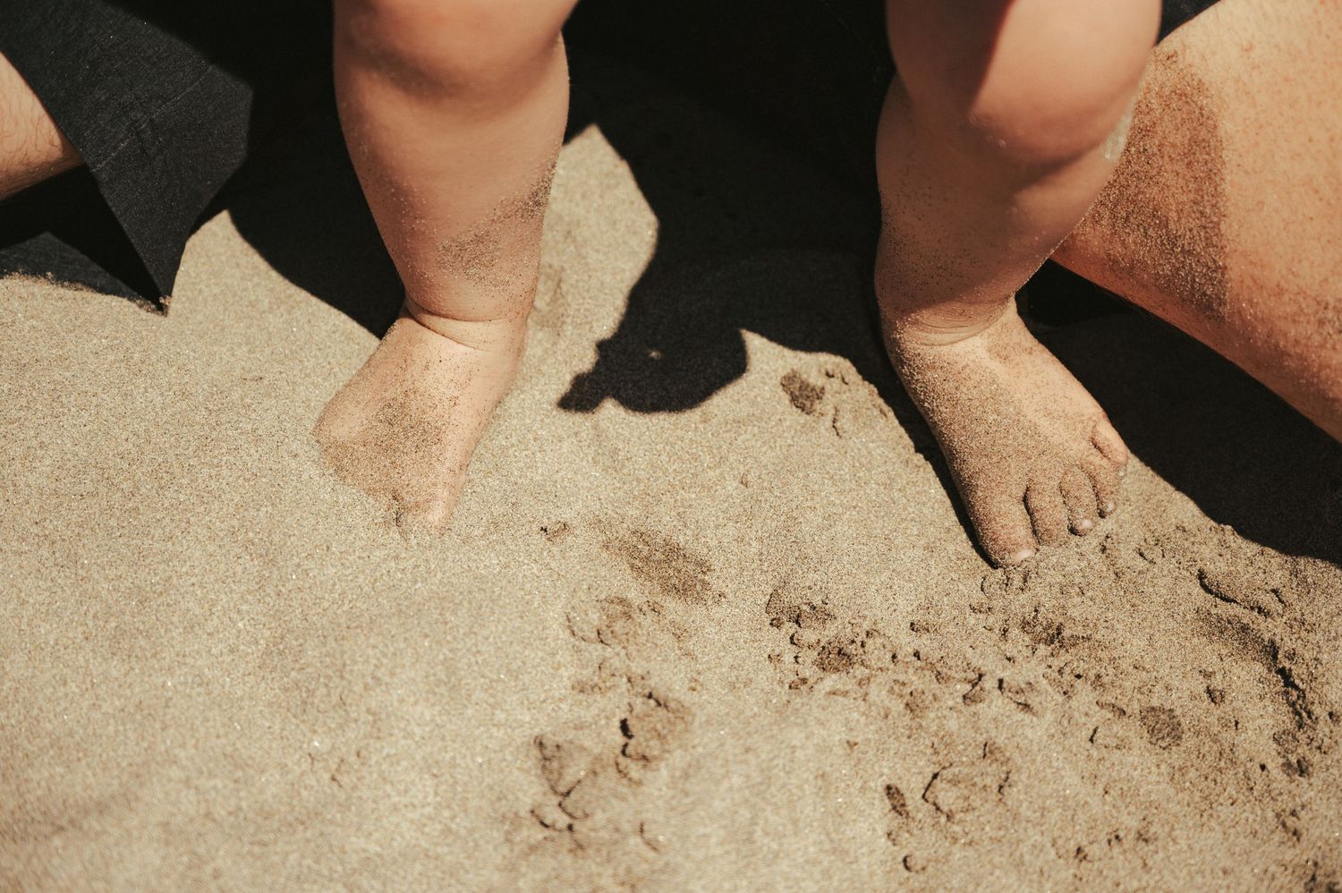Close-up shots of hands touching sand on a beach.