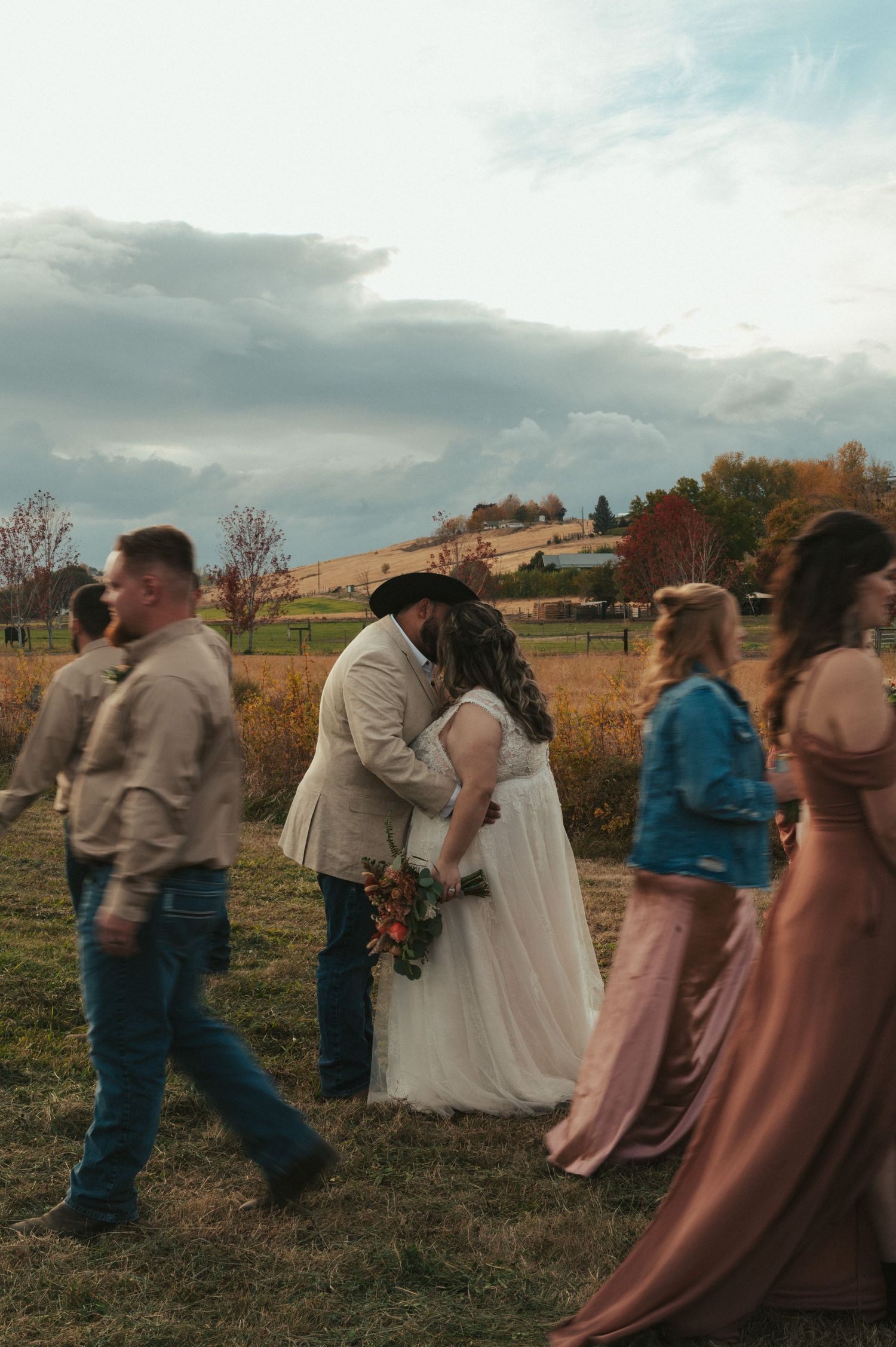 Wedding party walks through a golden field during an autumn countryside celebration.