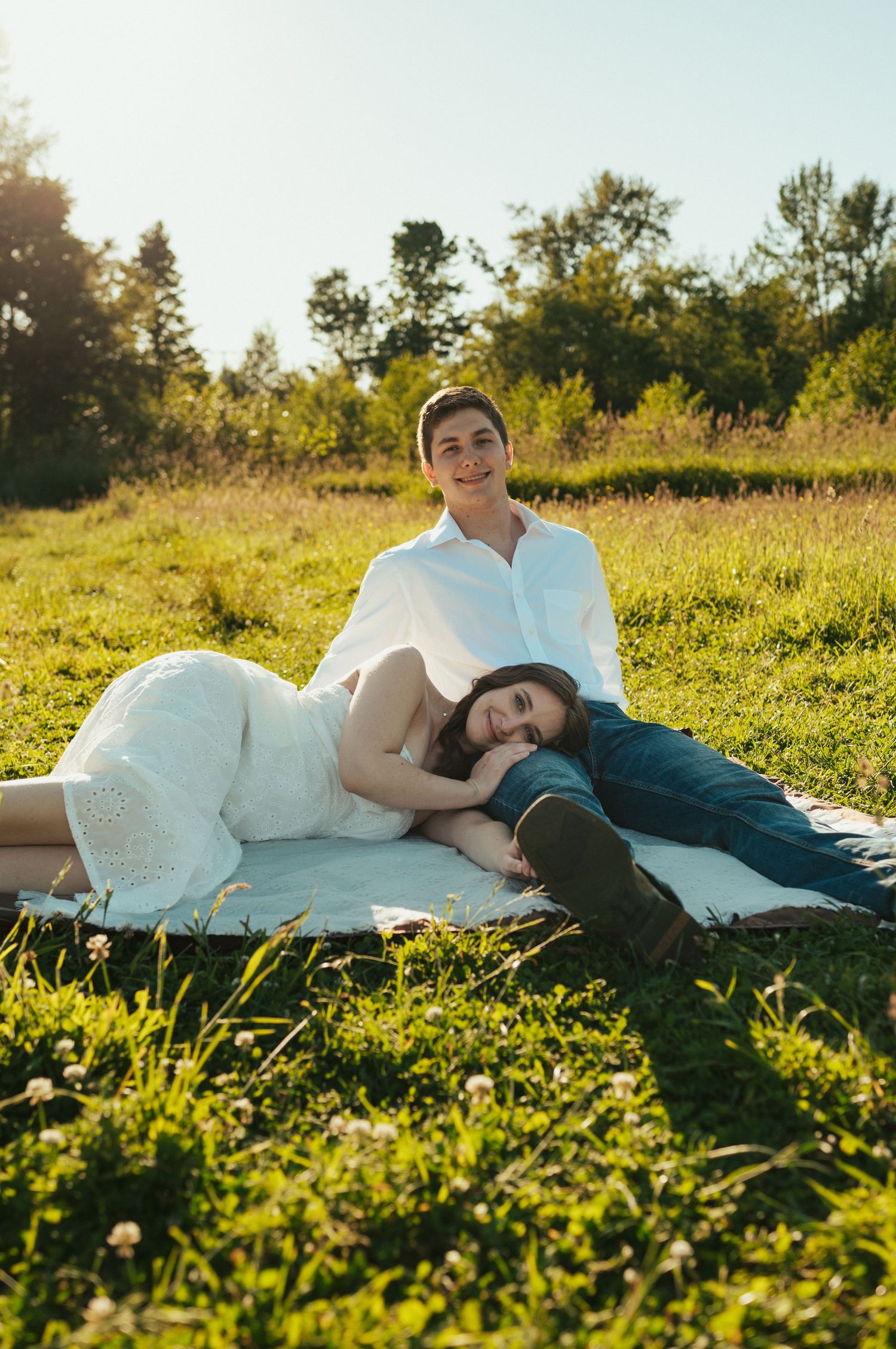 A couple relaxing on a blanket in a sunny meadow during golden hour.