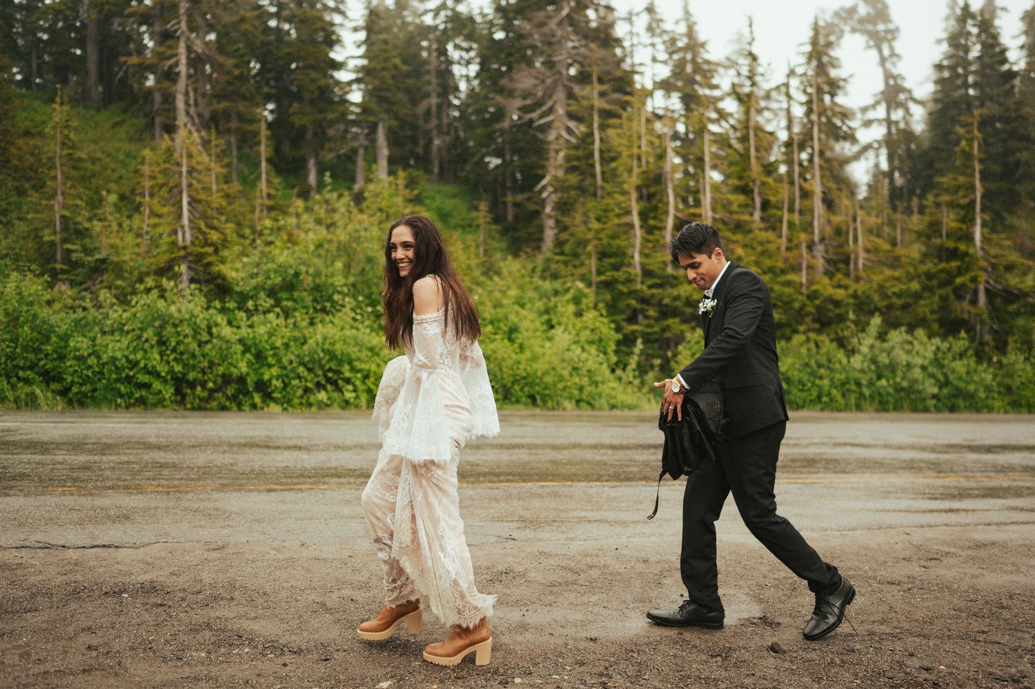Playful newlyweds walking and dancing in a forest clearing.