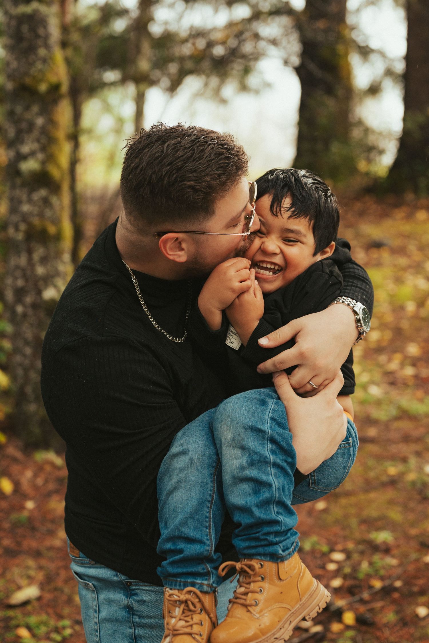 A playful moment of laughter and joy shared between parent and child in a forest setting.