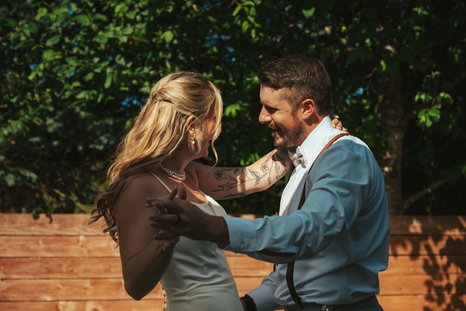 Couple dancing together during outdoor wedding celebration with natural backdrop.