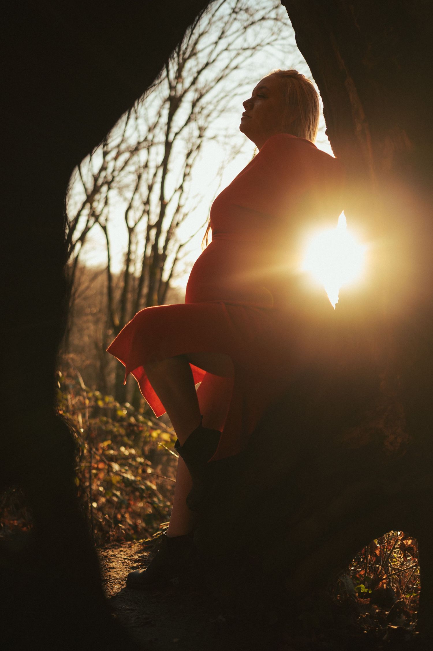Silhouette of a figure against bright sunlight through trees in nature.