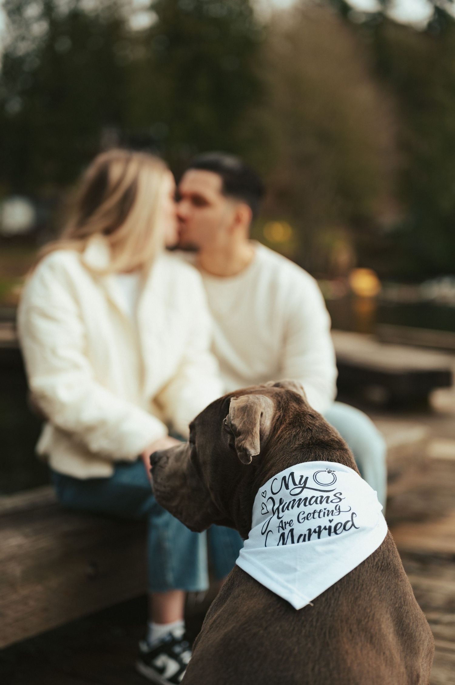 Couple wearing 'Getting Married' baseball caps share tender moments outdoors.