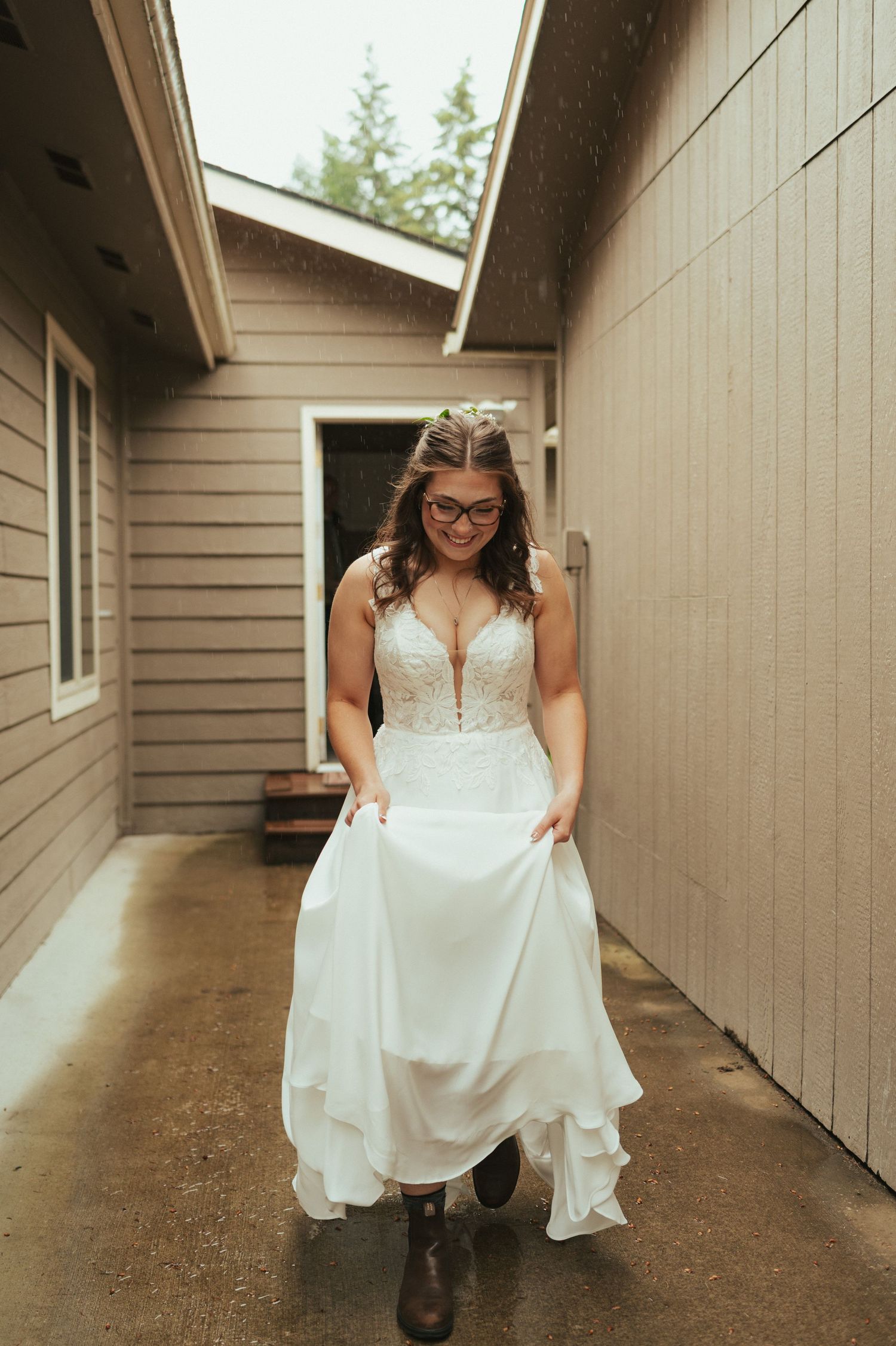 A bride in a white dress and boots poses in a casual hallway setting.
