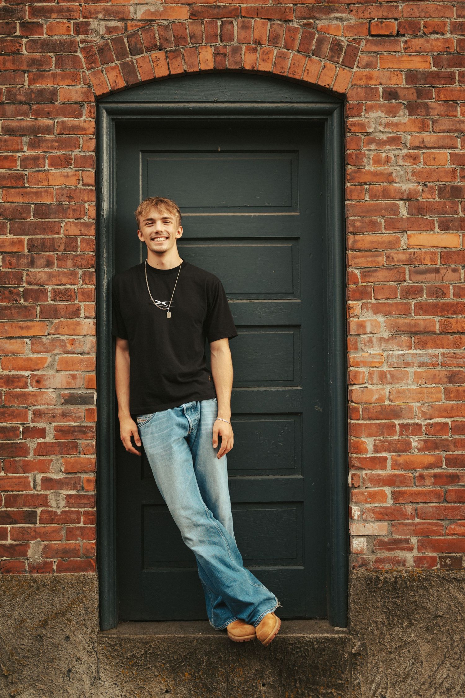A casual portrait session against red brick wall with dark painted doors.