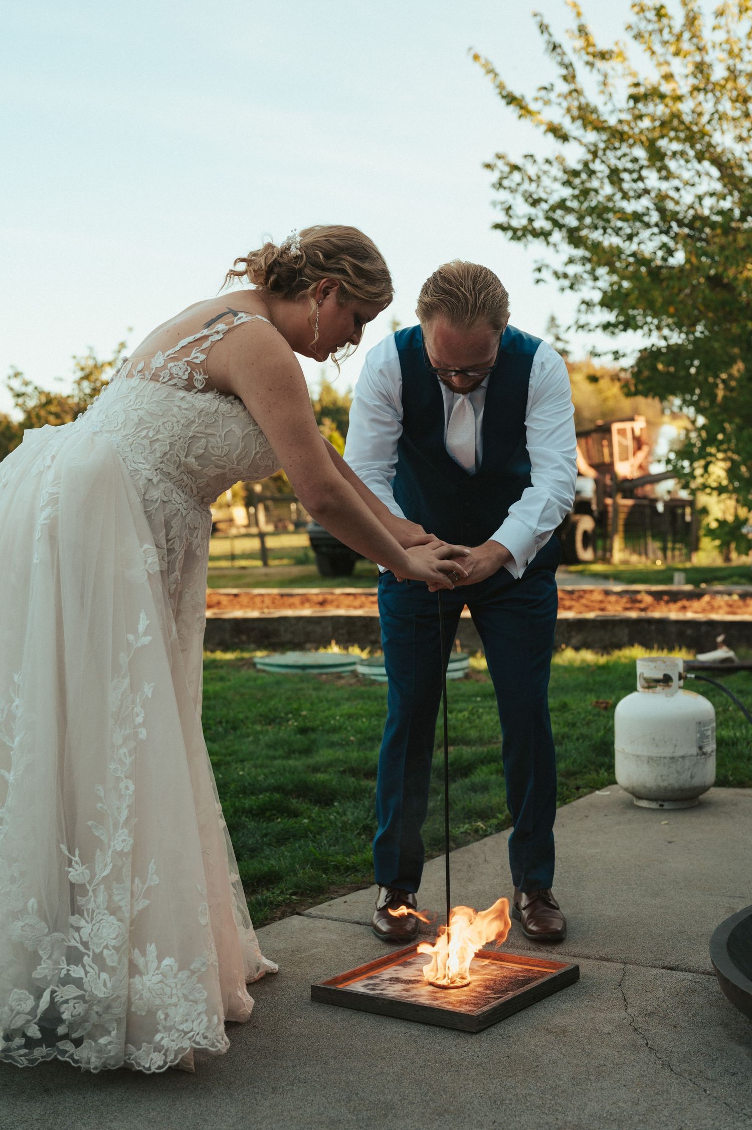 A couple performs a wedding ceremony ritual involving fire on an outdoor patio.