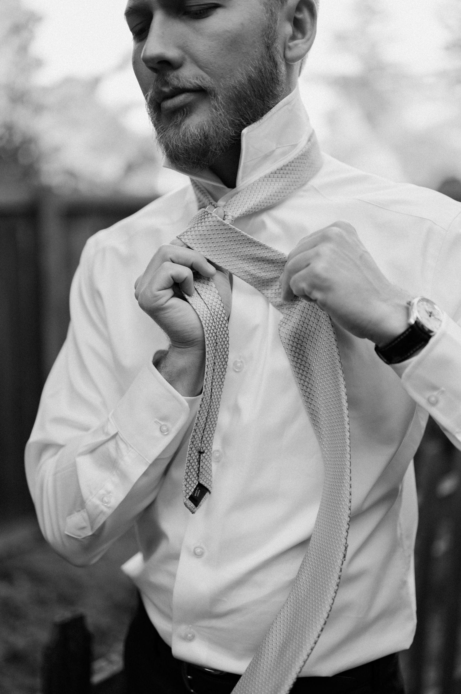 Close-up sequence of someone adjusting a patterned tie with a white dress shirt.
