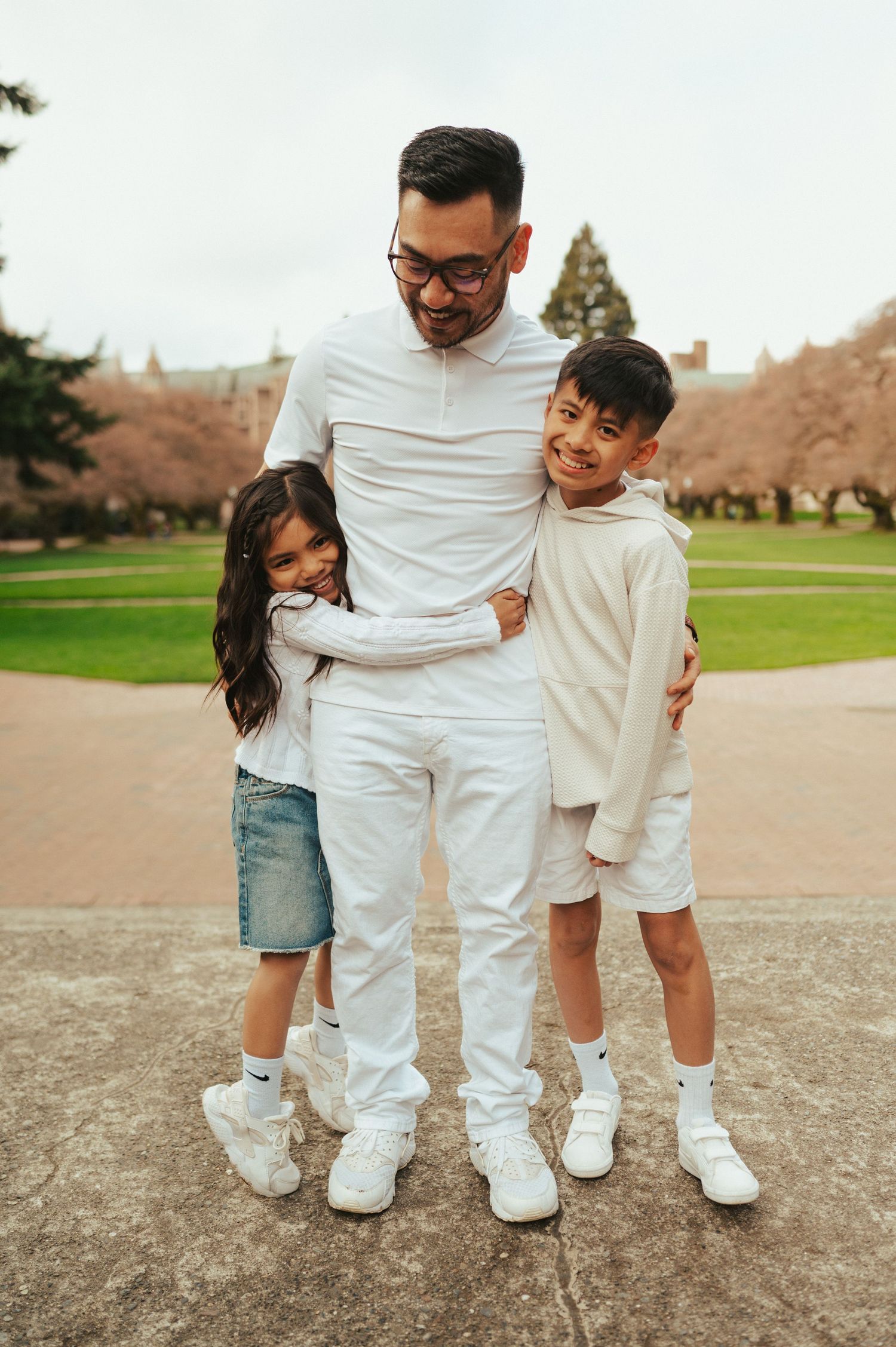 A family group in coordinated white outfits poses together on a campus pathway.