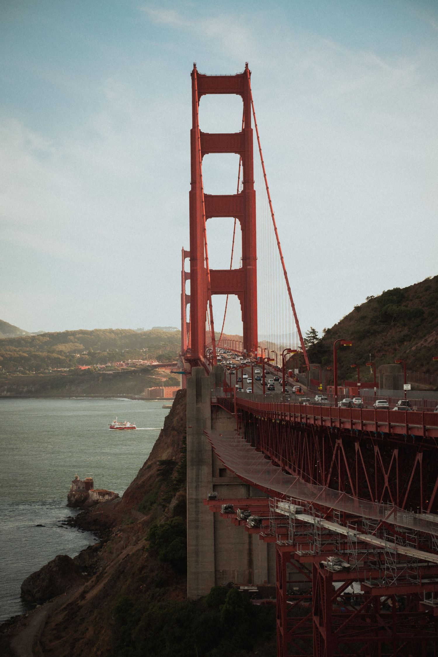 View of the iconic Golden Gate Bridge in San Francisco with its distinctive red towers against a cloudy sky over the bay.
