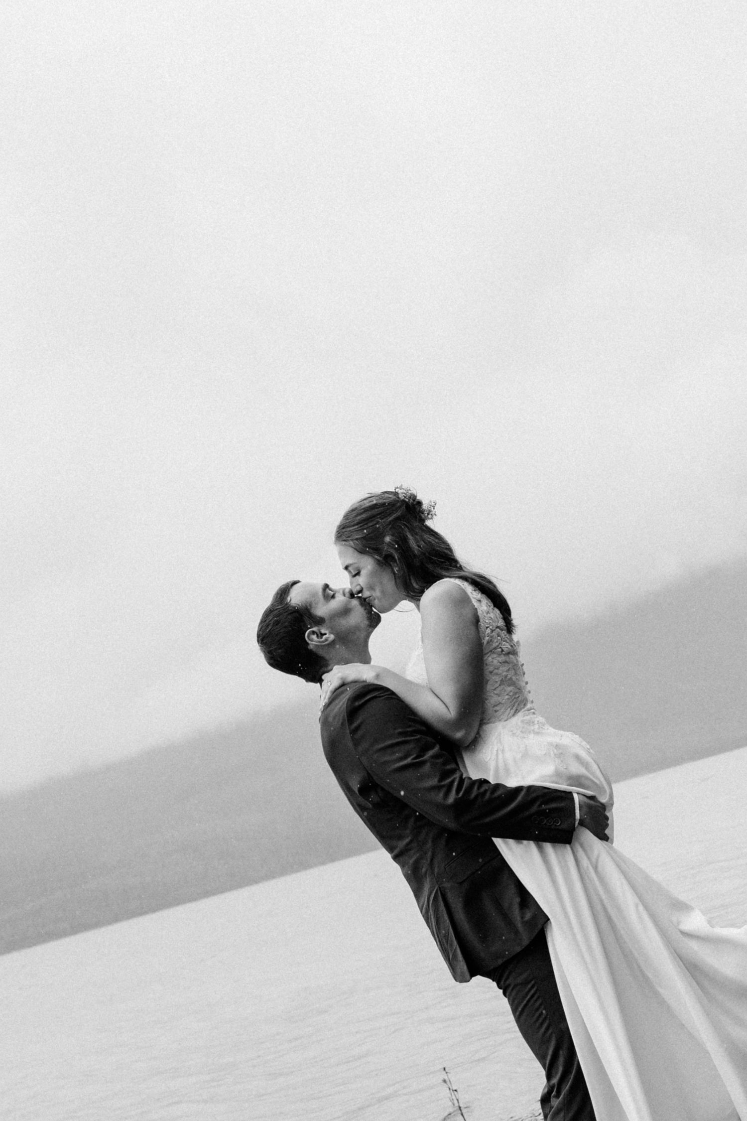 Intimate black and white wedding portrait showing couple's silhouette against bright background.