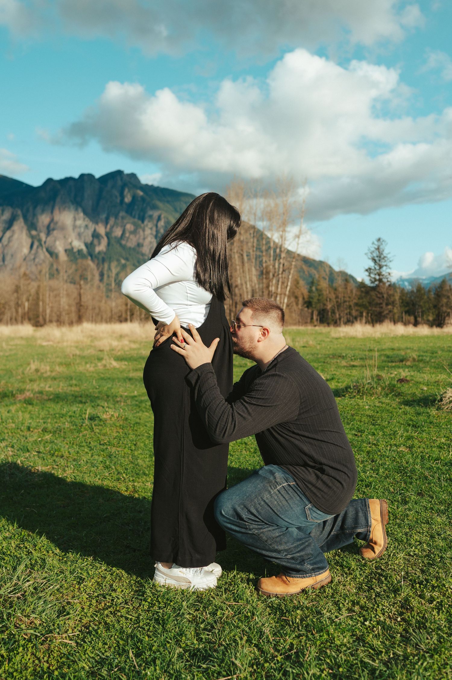 Playful interactions between loved ones on green grass with mountains in the background.