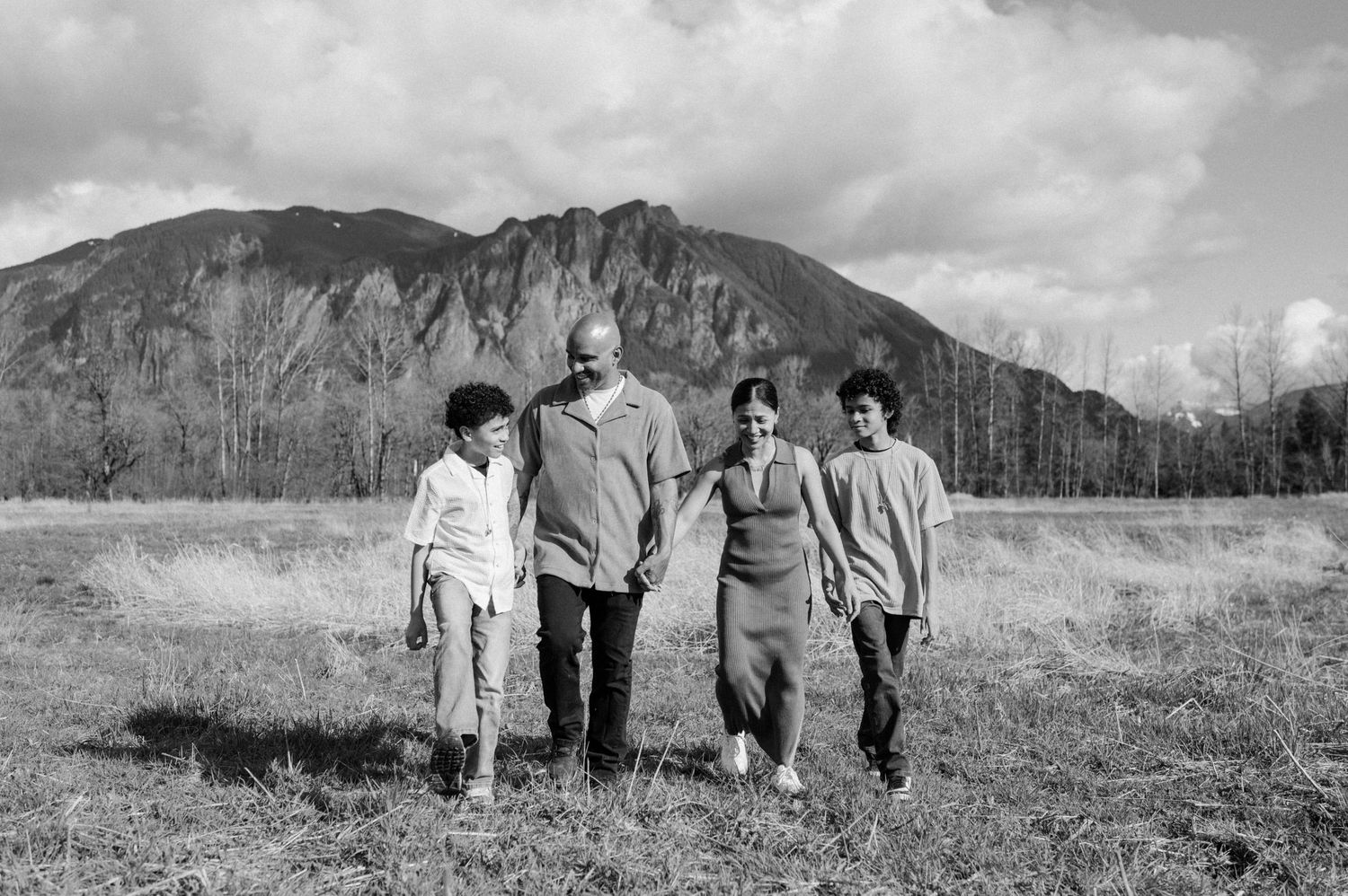 A black and white landscape photo showing people walking together with mountains in the distance.