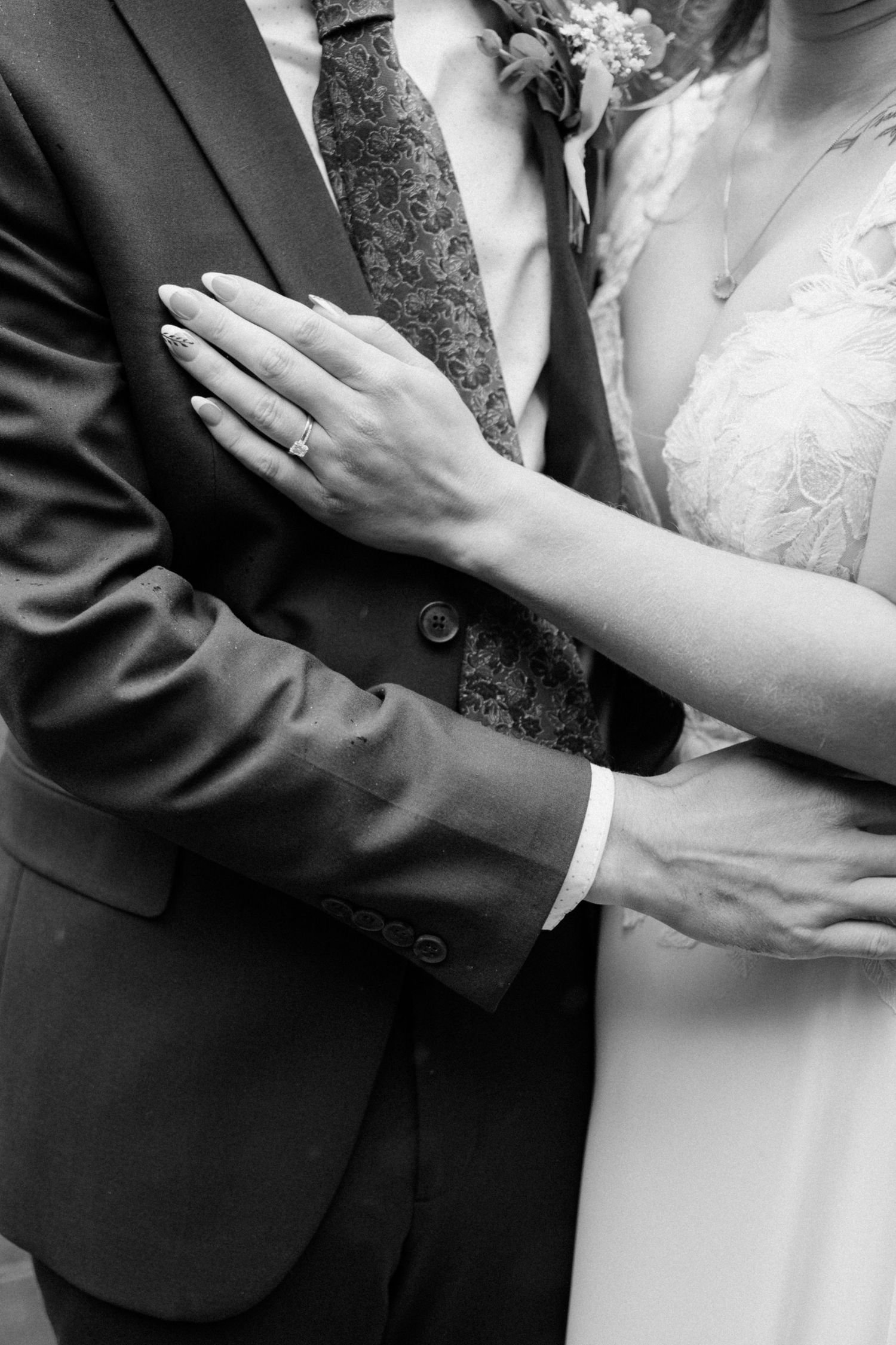 Black and white close-up shots of newlyweds embracing, focusing on hands and formal attire.