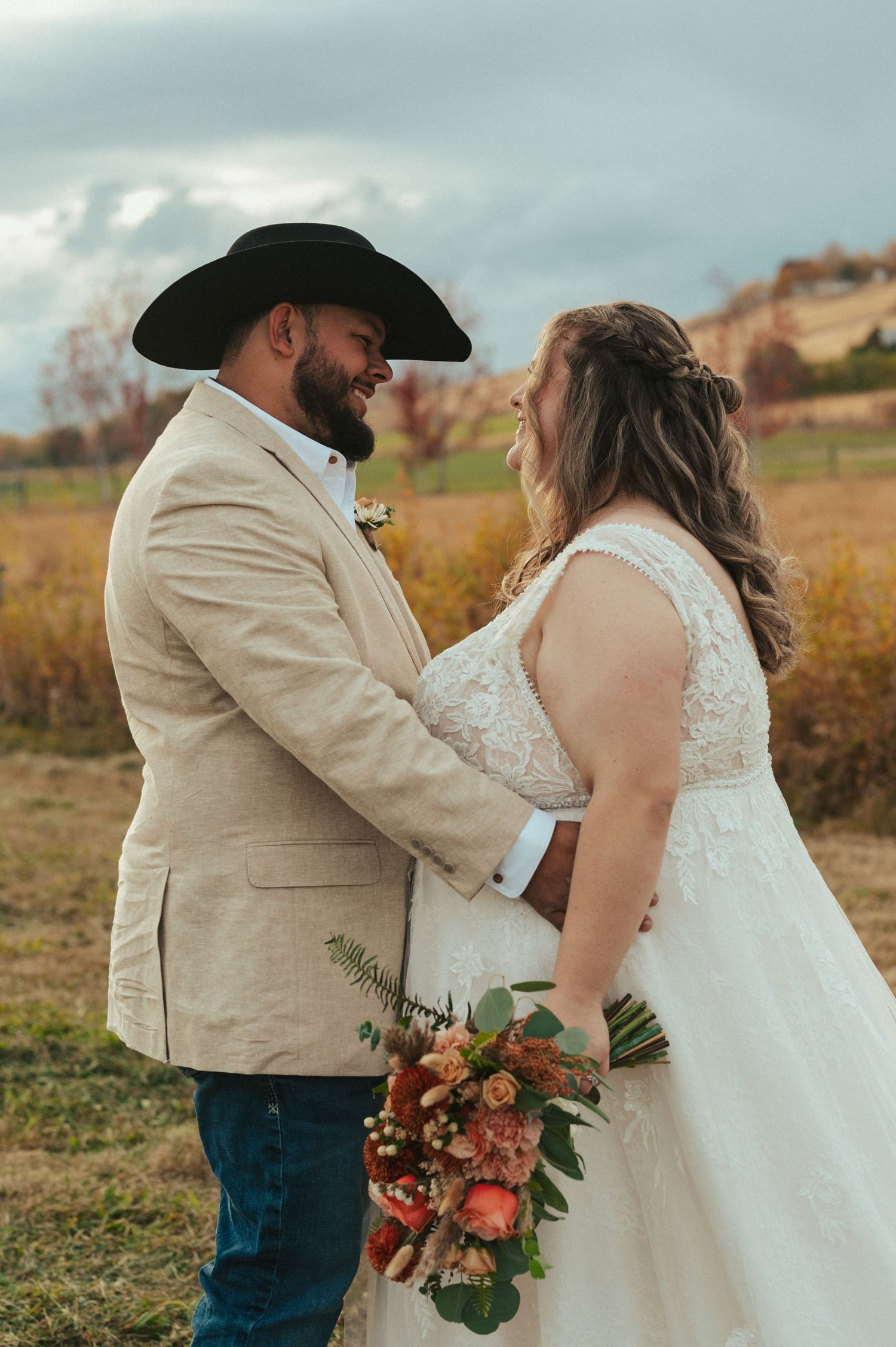 A couple shares an intimate moment in a rustic outdoor setting during their autumn wedding.
