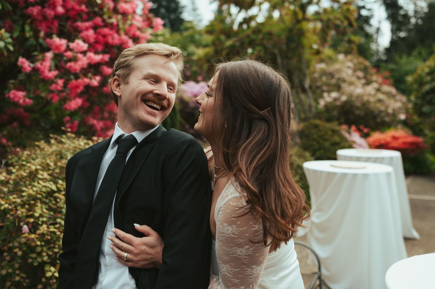 A joyful celebration moment captured outdoors among blooming pink azalea bushes.